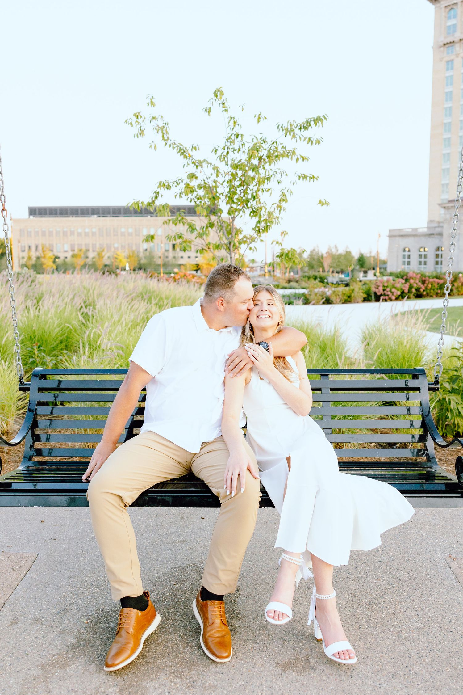 Engaged couple embracing on bench at Michigan Central Station in Detroit, MI