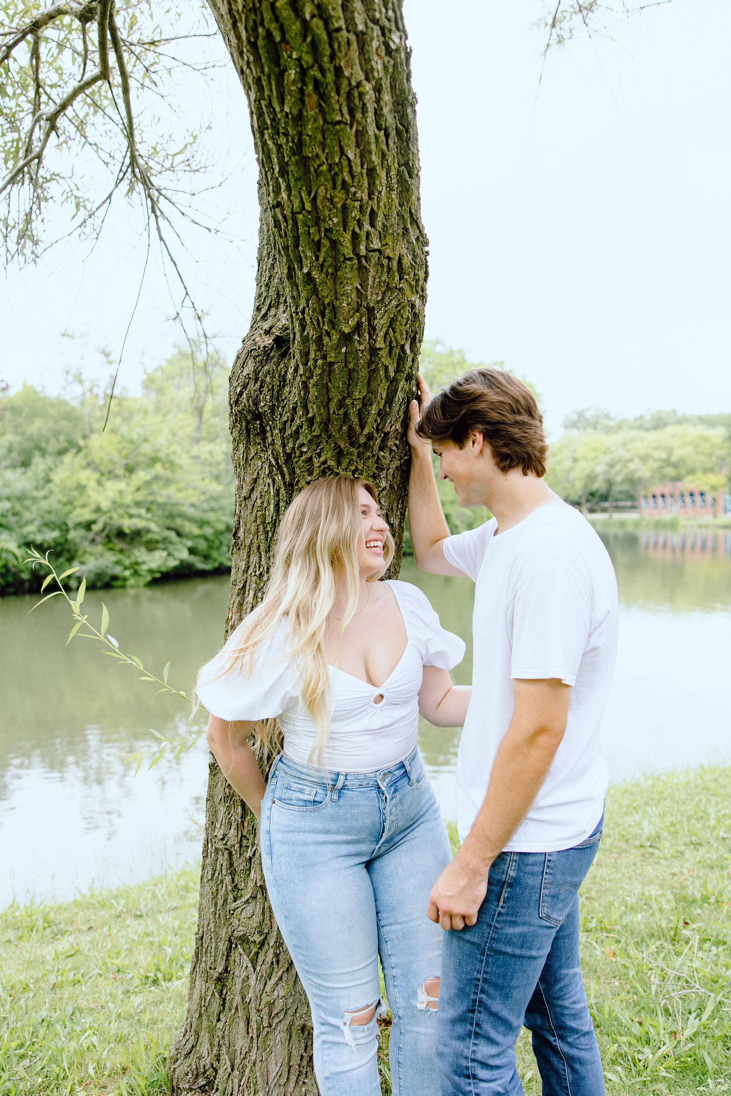 Engaged couple kissing against tree at Greenfield Village in Dearborn, MI