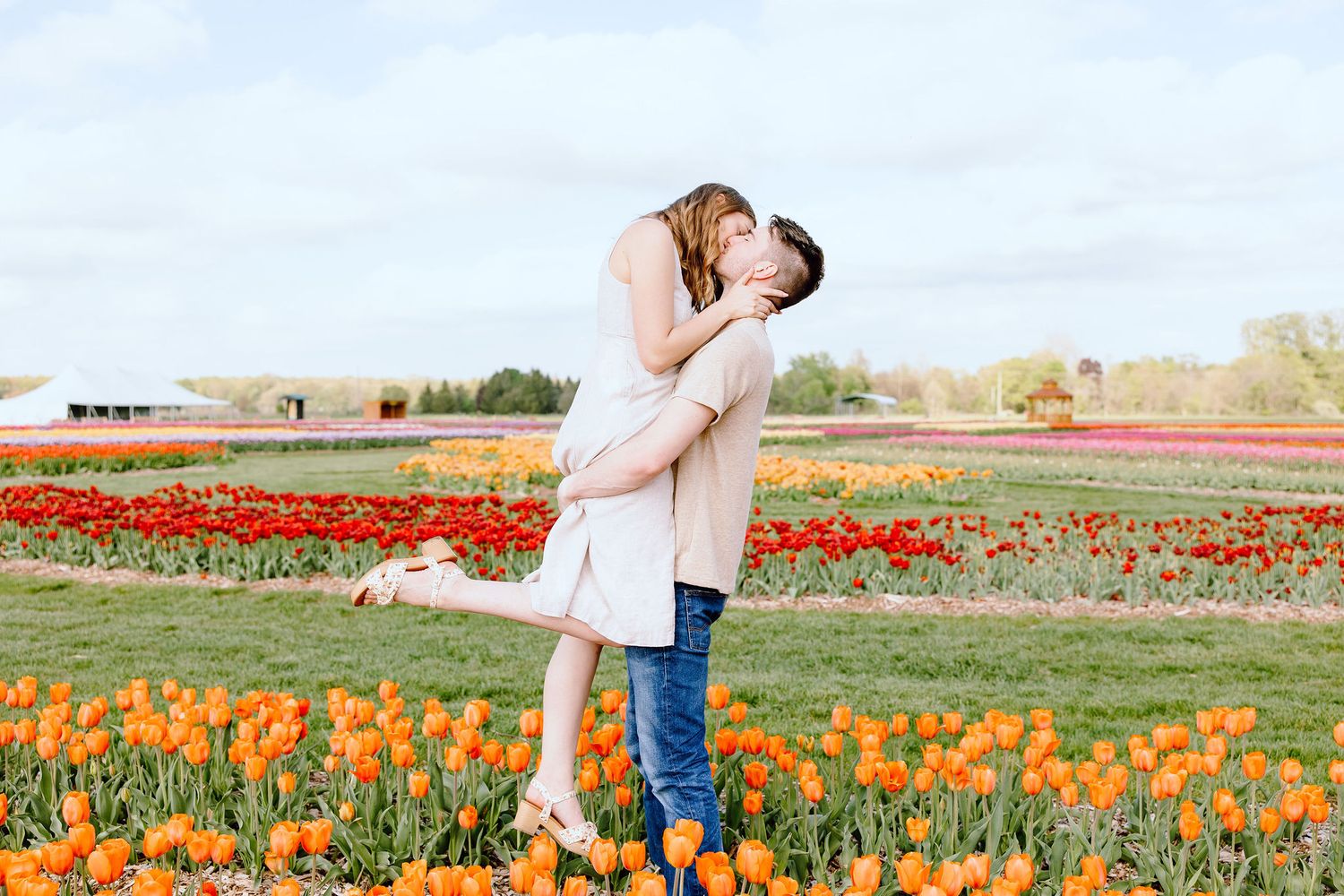 Man lifting woman at DeBuck's tulip field engagement session in Belleville, MI
Engaged couple sitting on cabin at DeBuck's tulip field