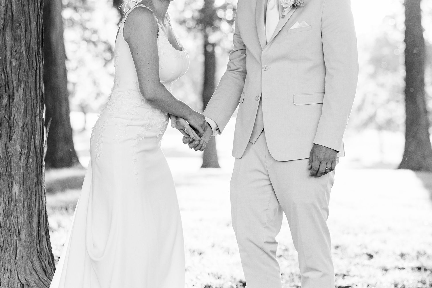 Married couple holding hands during golden hour at Lapeer Country Club forest wedding in Michigan