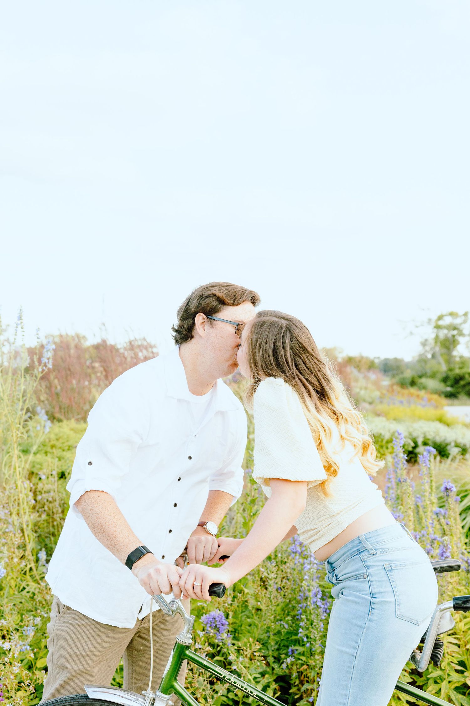Engaged couple kissing on tandem bike at Belle Isle summer engagement session in Detroit, MI