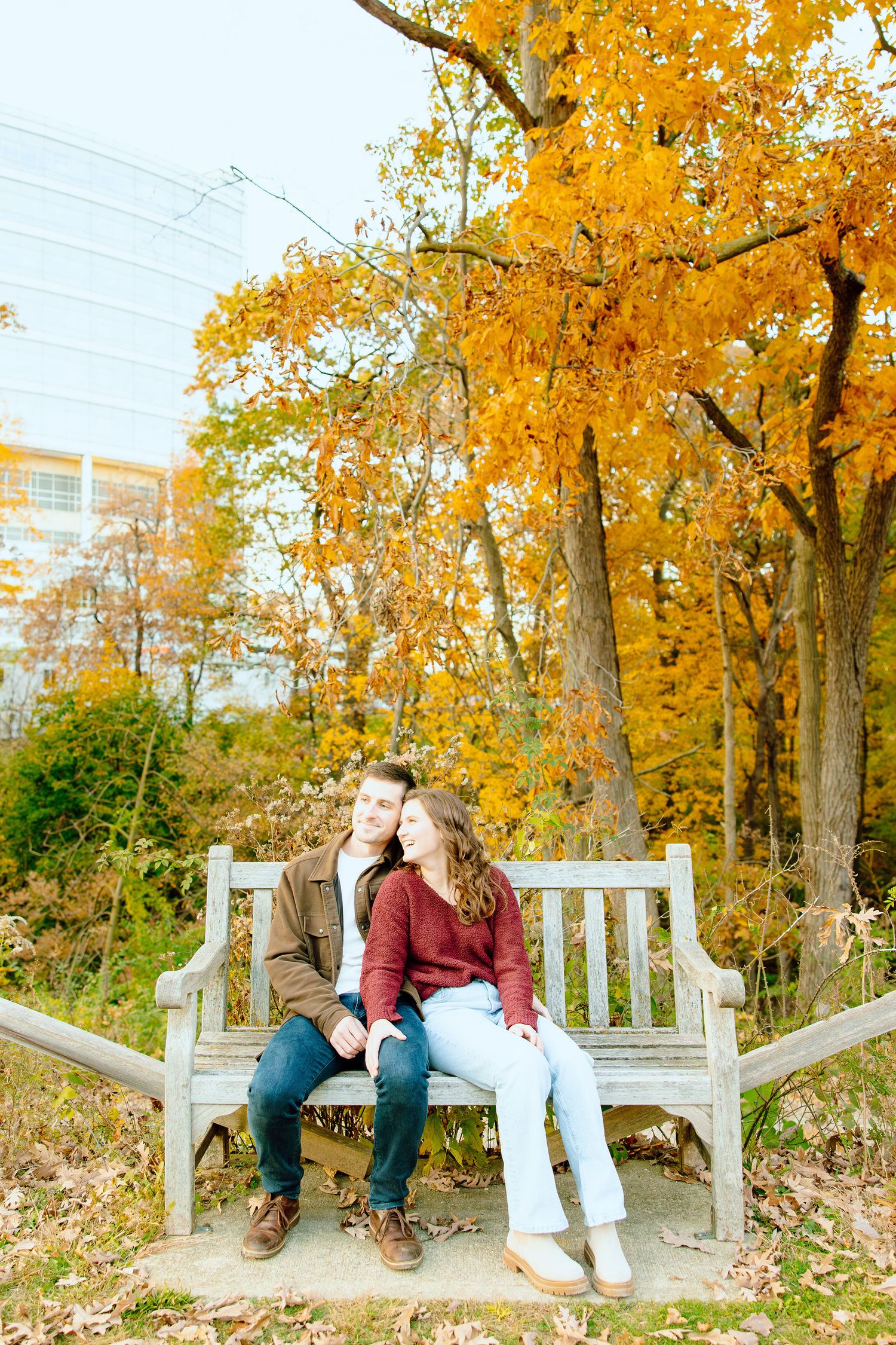 Engaged couple embracing on bench at Nichols Arboretum in Ann Arbor, MI