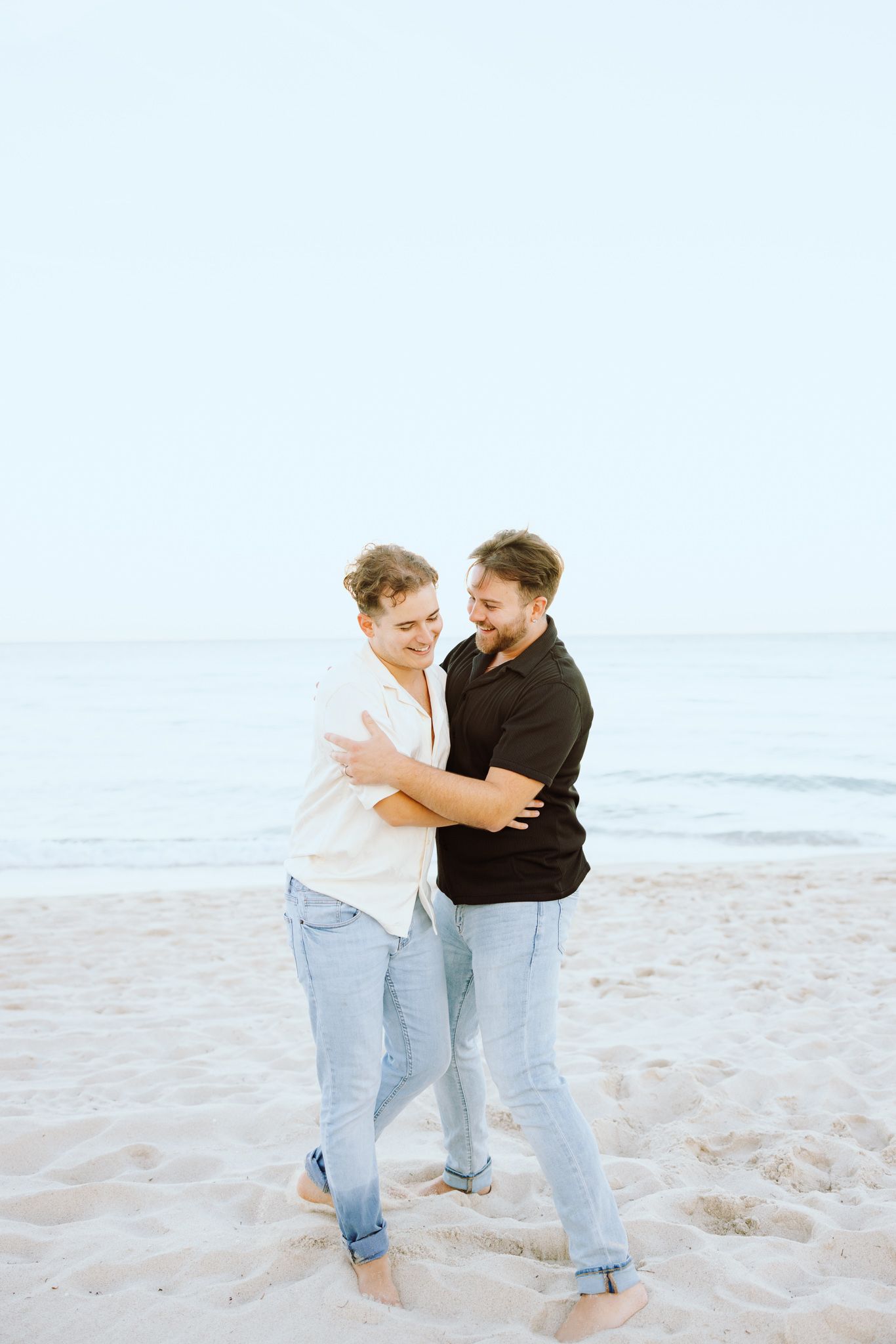 LGBTQ+ couple hugging and laughing on North Miami Beach in Florida