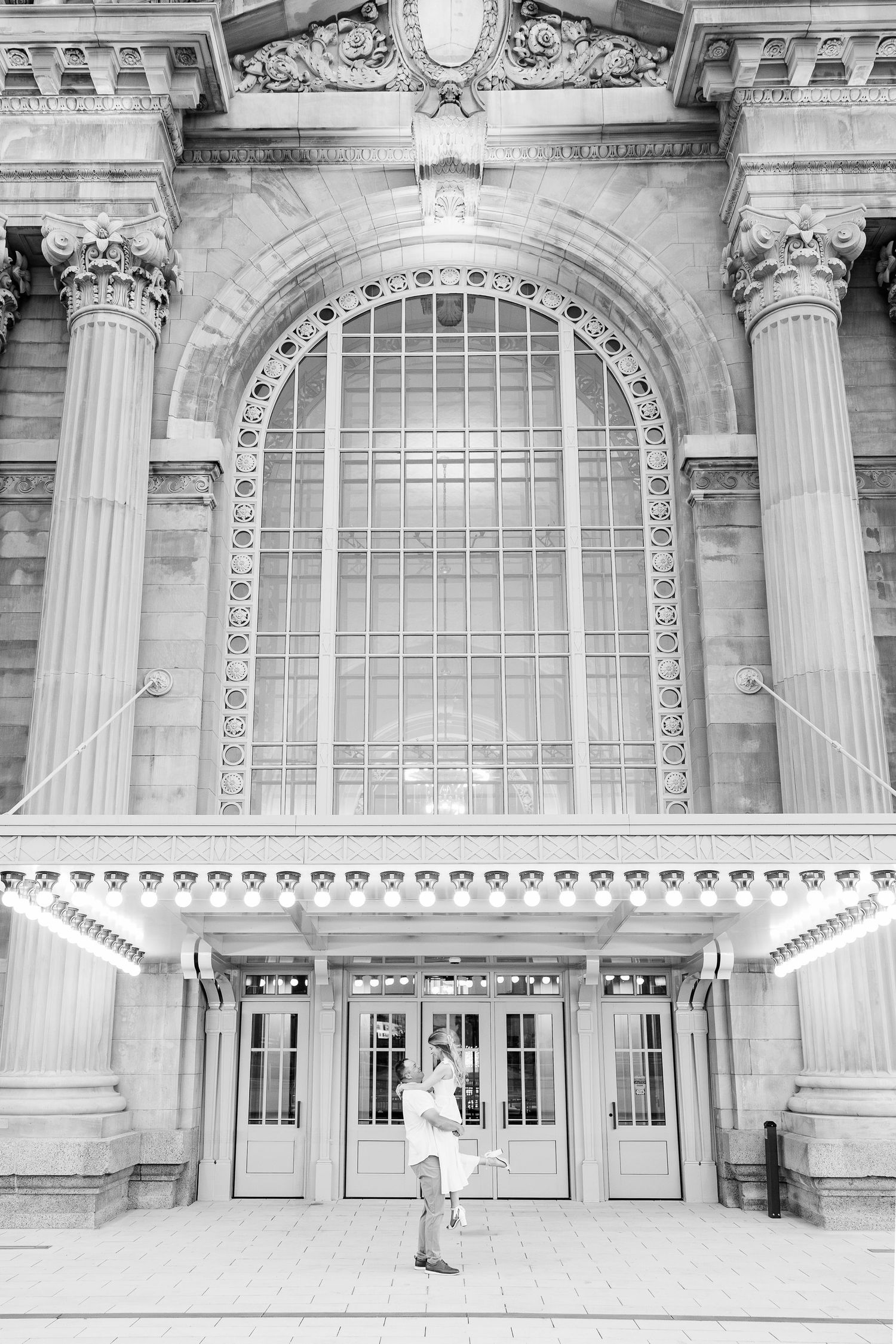 Man lifting woman at Michigan Central Station summer engagement session in Detroit, MI