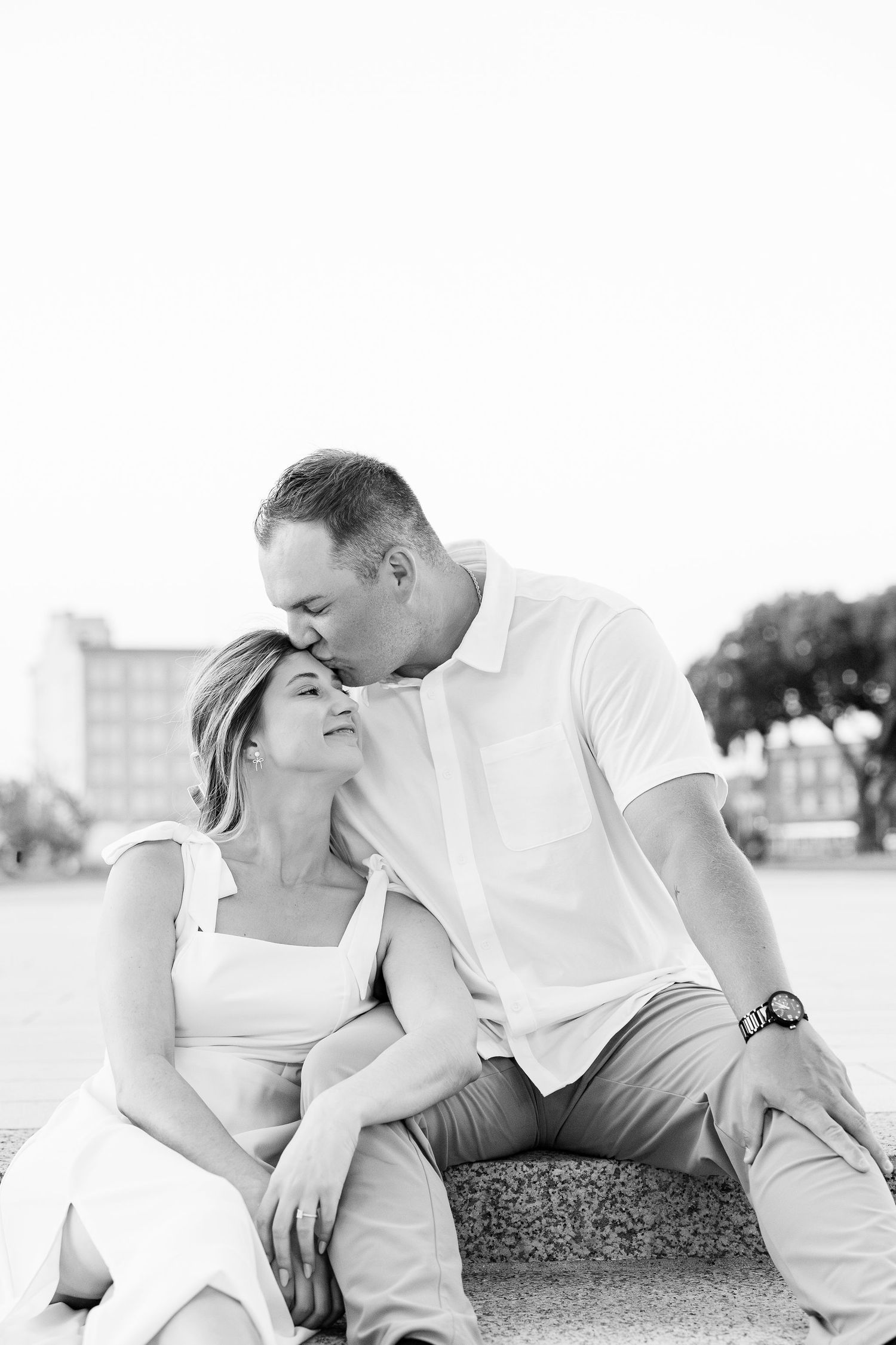 Engaged couple kissing on bench at Michigan Central Station in Detroit, MI