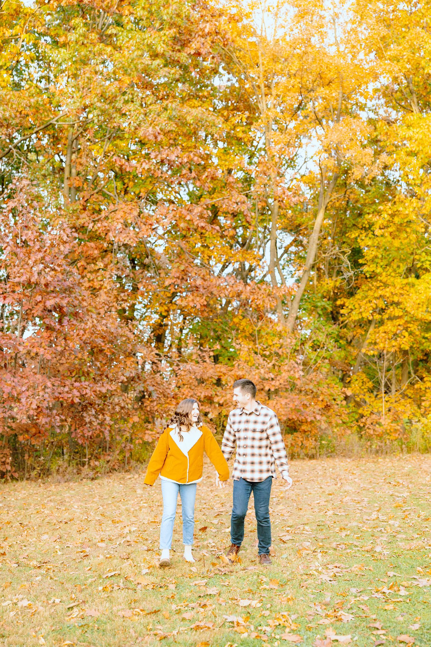 Engaged couple walking in forest at Nichols Arboretum fall engagement session in Ann Arbor, MI