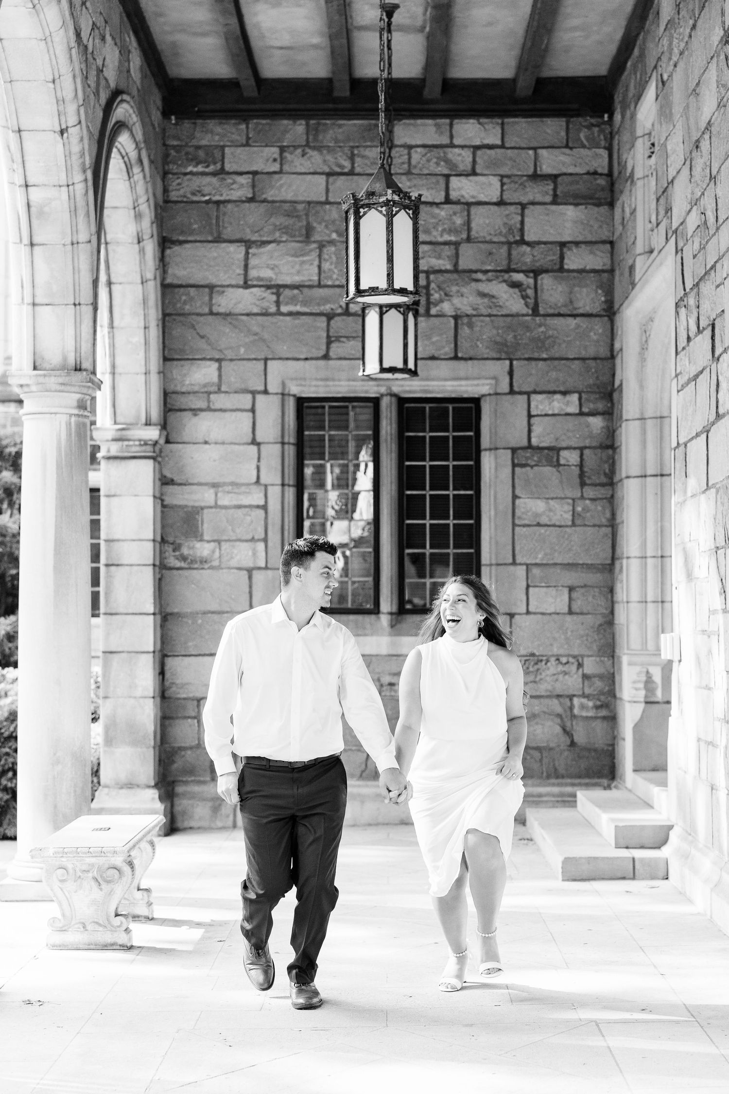 Engaged couple running and holding hands at the UofM Law Quad engagement session in Ann Arbor, MI