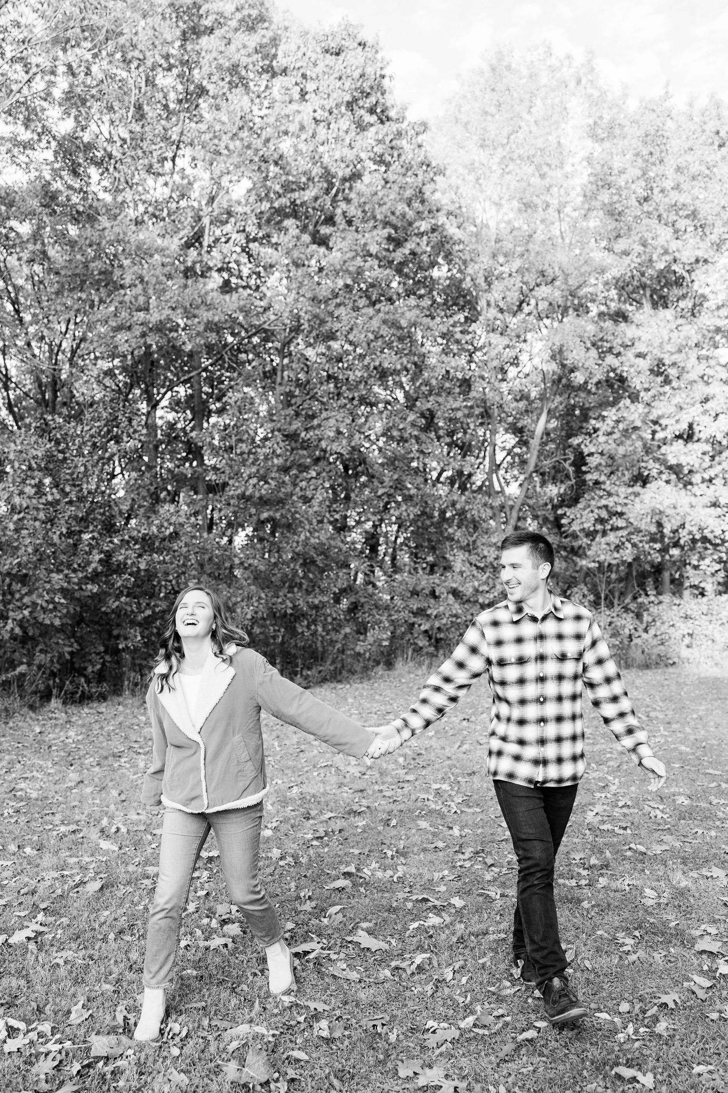 Engaged couple walking in forest at Nichols Arboretum fall engagement session in Ann Arbor, MI