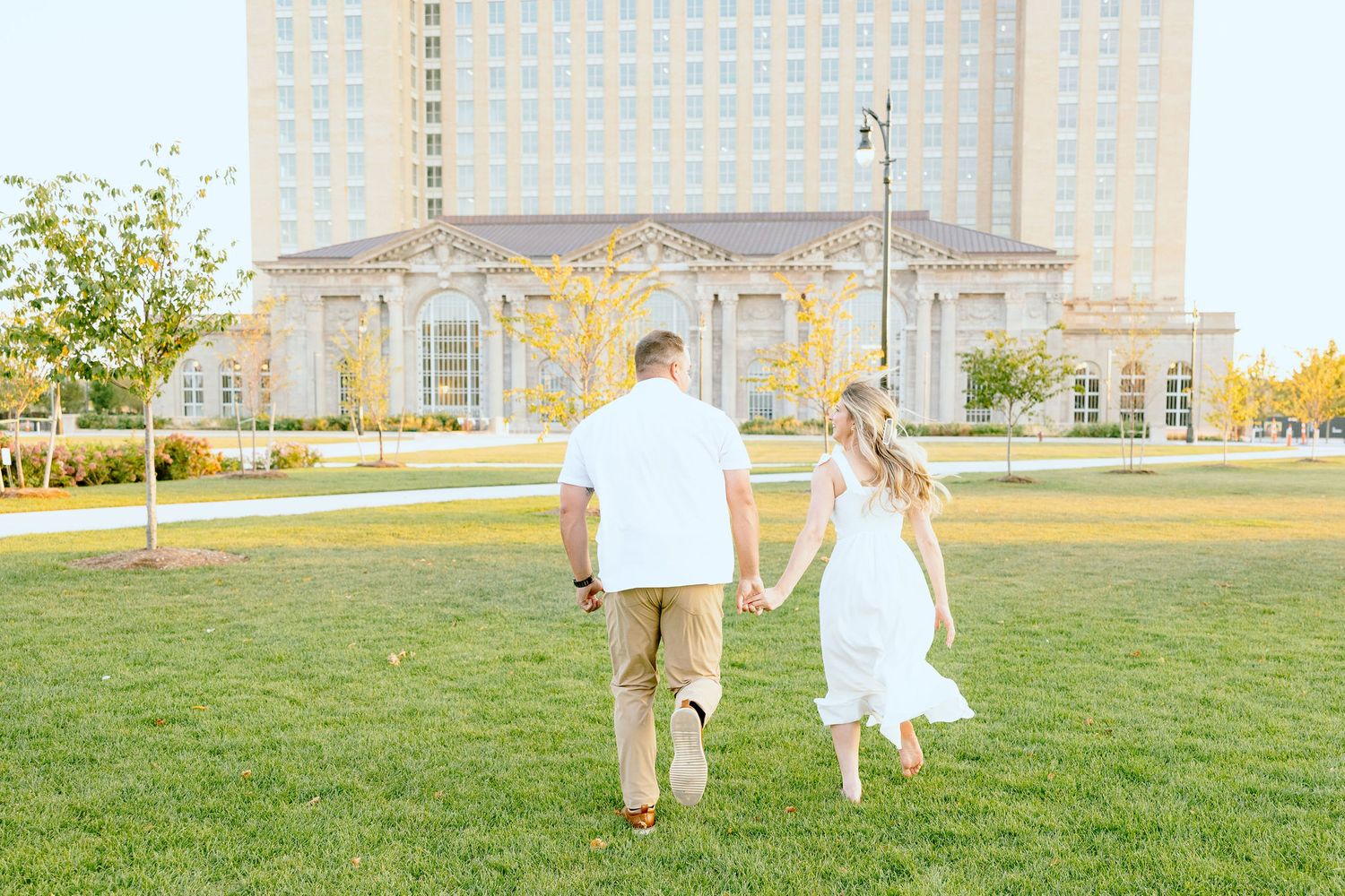 Engaged couple running and holding hands at Michigan Central Station summer engagement session in Detroit, MI