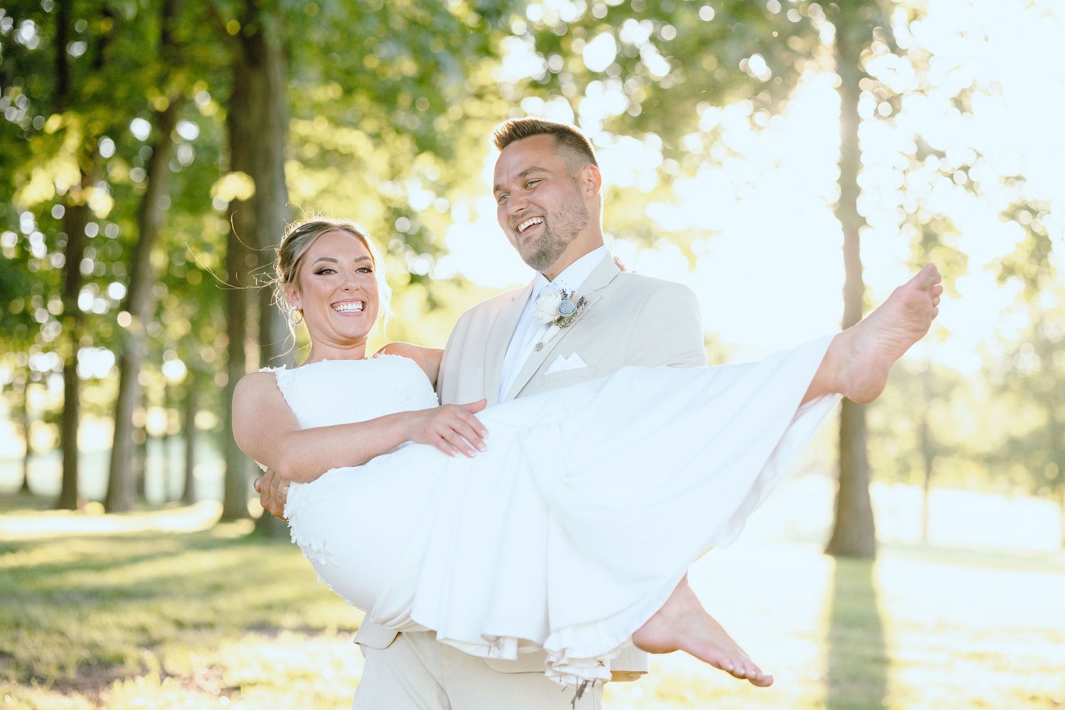 Groom carrying bride during golden hour at Lapeer Country Club forest wedding in Michigan
