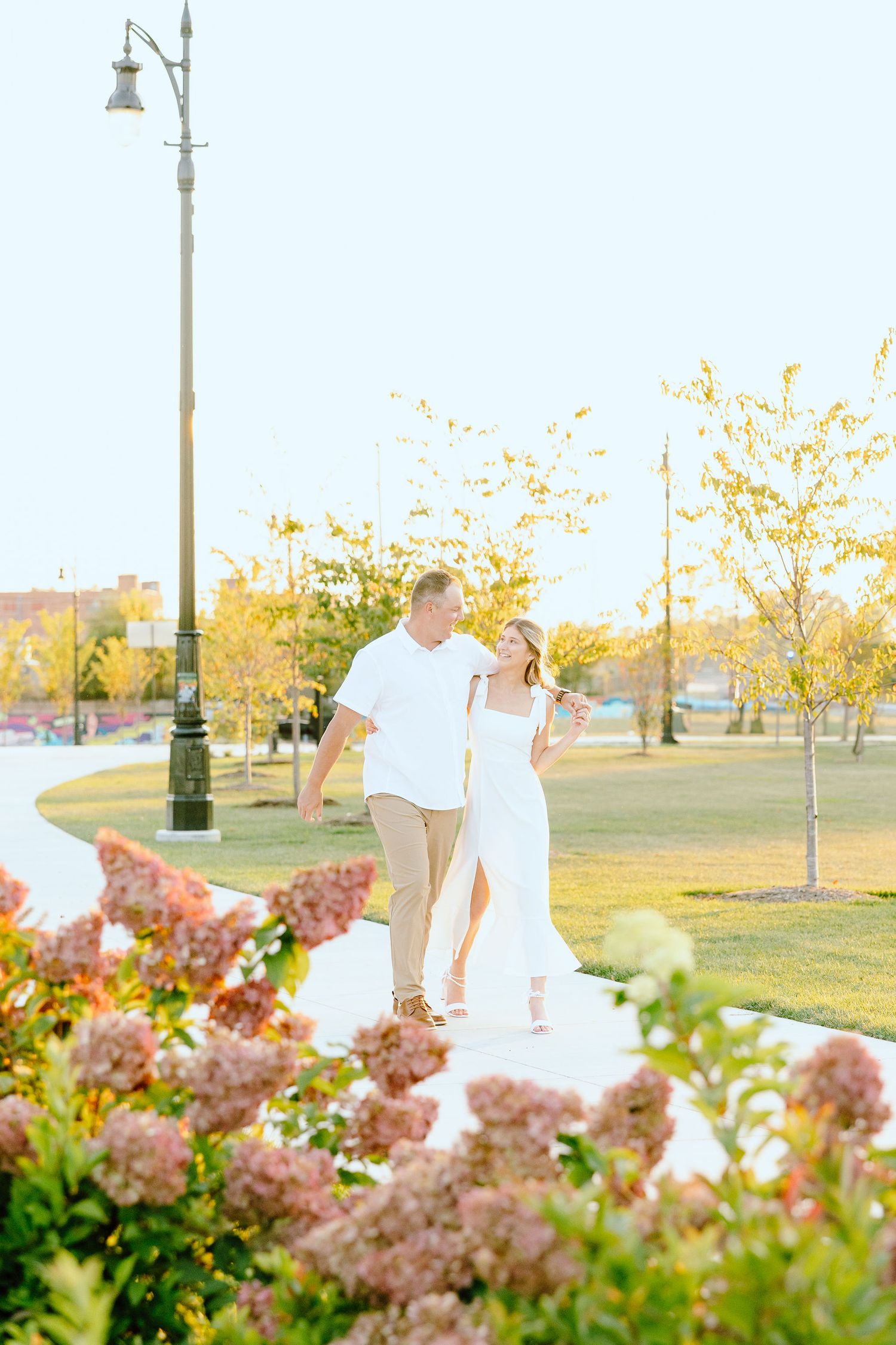 Engaged couple walking and holding hands at Michigan Central Station summer engagement session in Detroit, MI