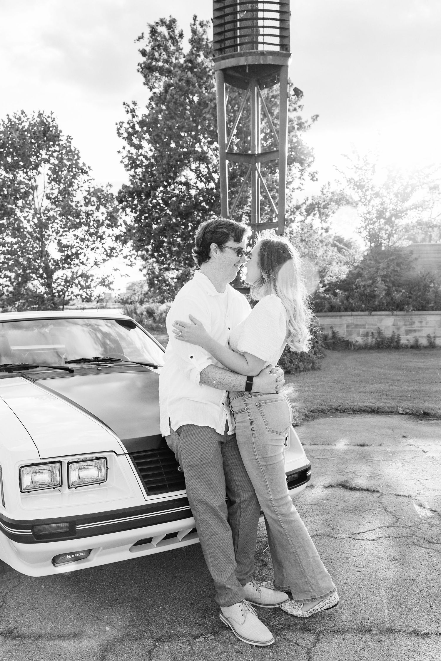 Engaged couple kissing against vintage car at Belle Isle summer engagement session in Detroit, MI