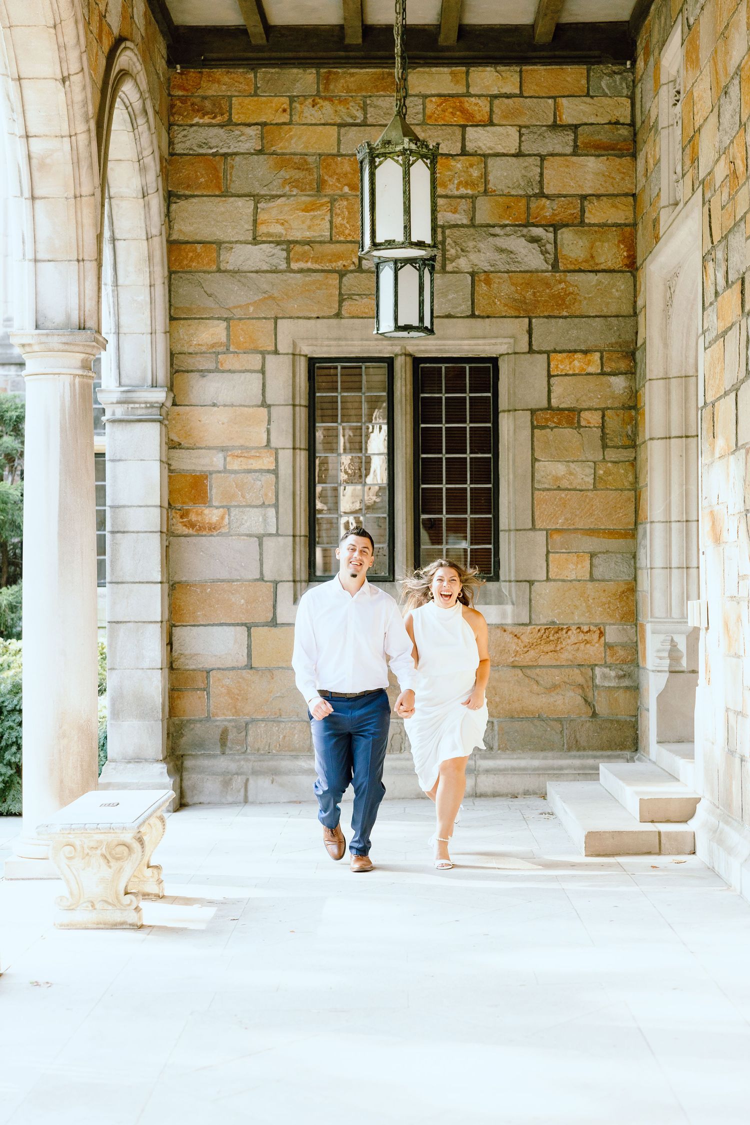 Engaged couple running and holding hands at the UofM Law Quad engagement session in Ann Arbor, MI