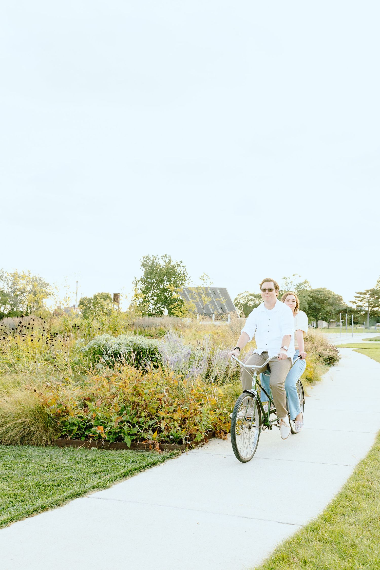 Engaged couple biking on tandem bike at Belle Isle summer engagement session in Detroit, MI
