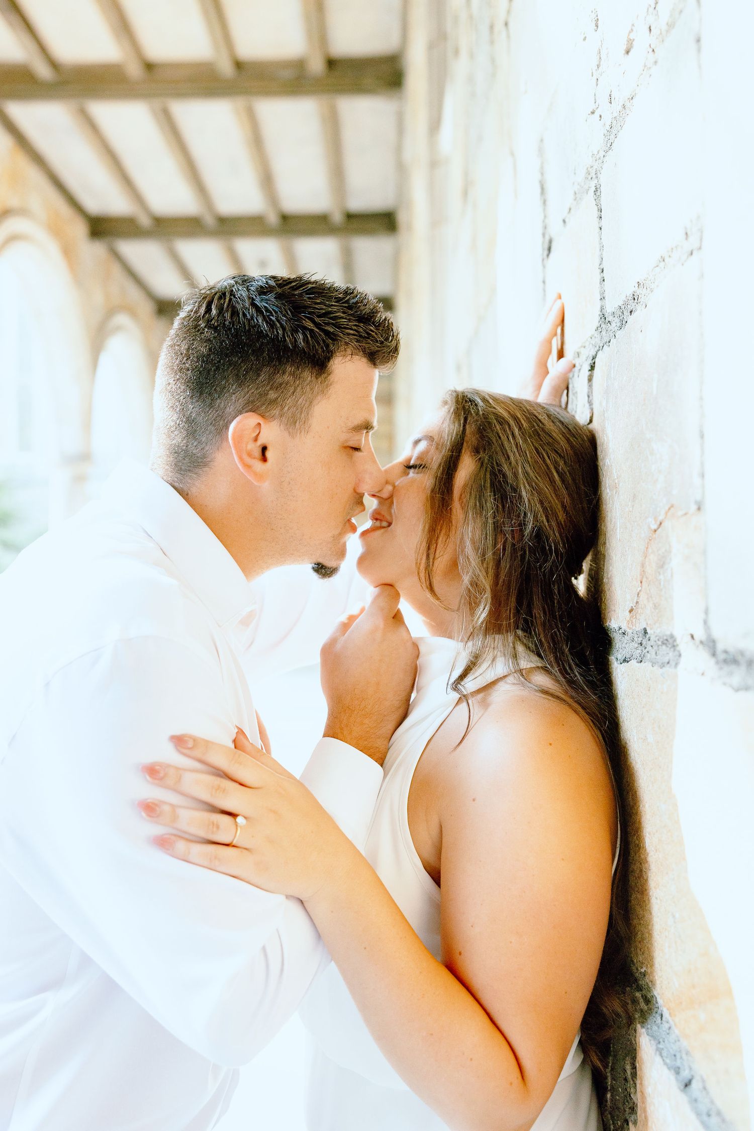 Engaged couple kissing against wall at the University of Michigan Law Quad engagement session in Ann Arbor, MI