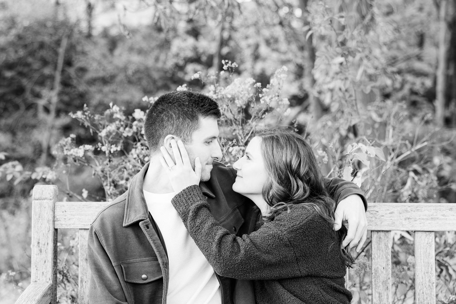 Engaged couple embracing on bench at Nichols Arboretum in Ann Arbor, MI