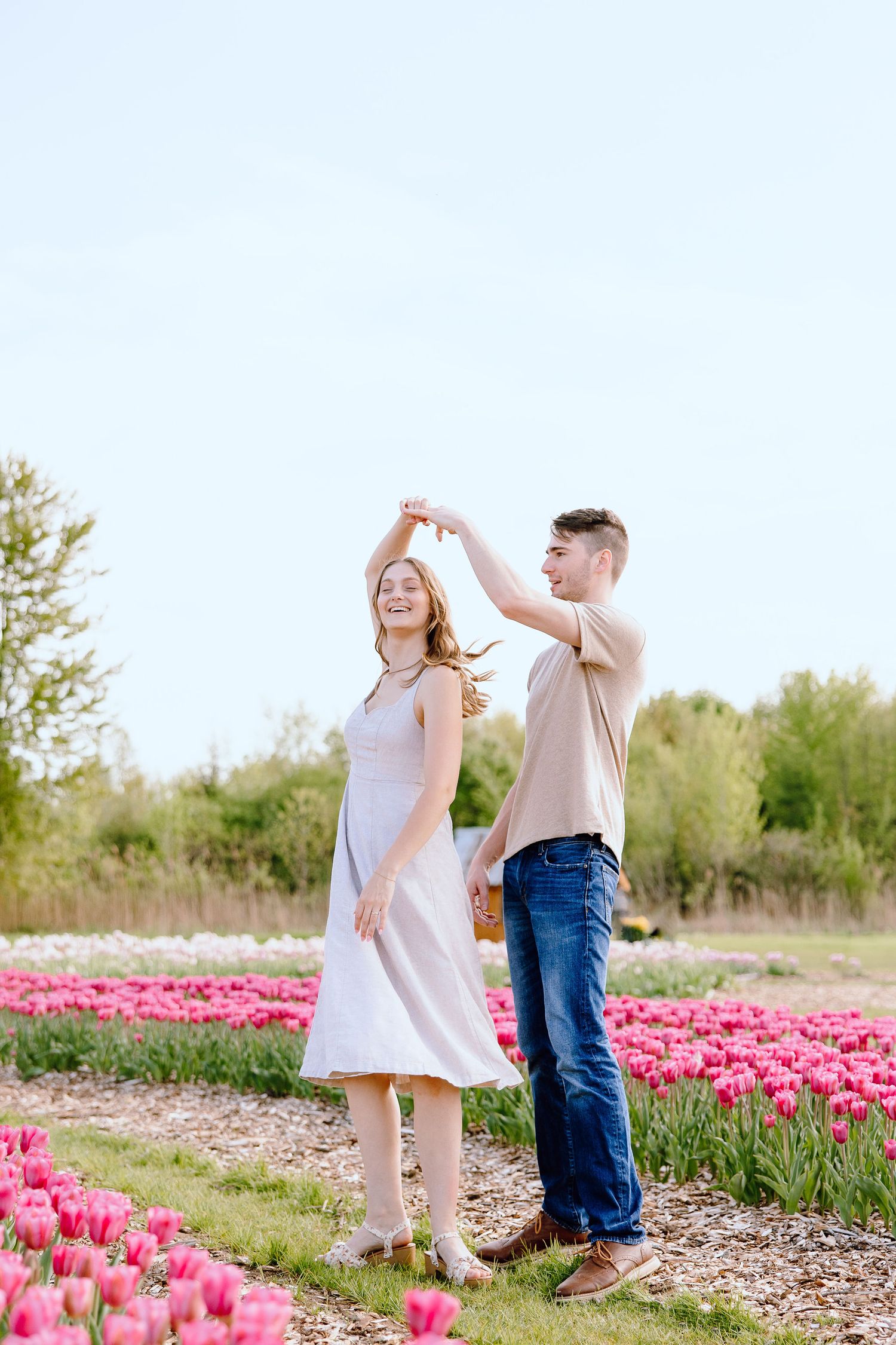 Engaged couple twirling at DeBuck's tulip field spring engagement session in Belleville, MI