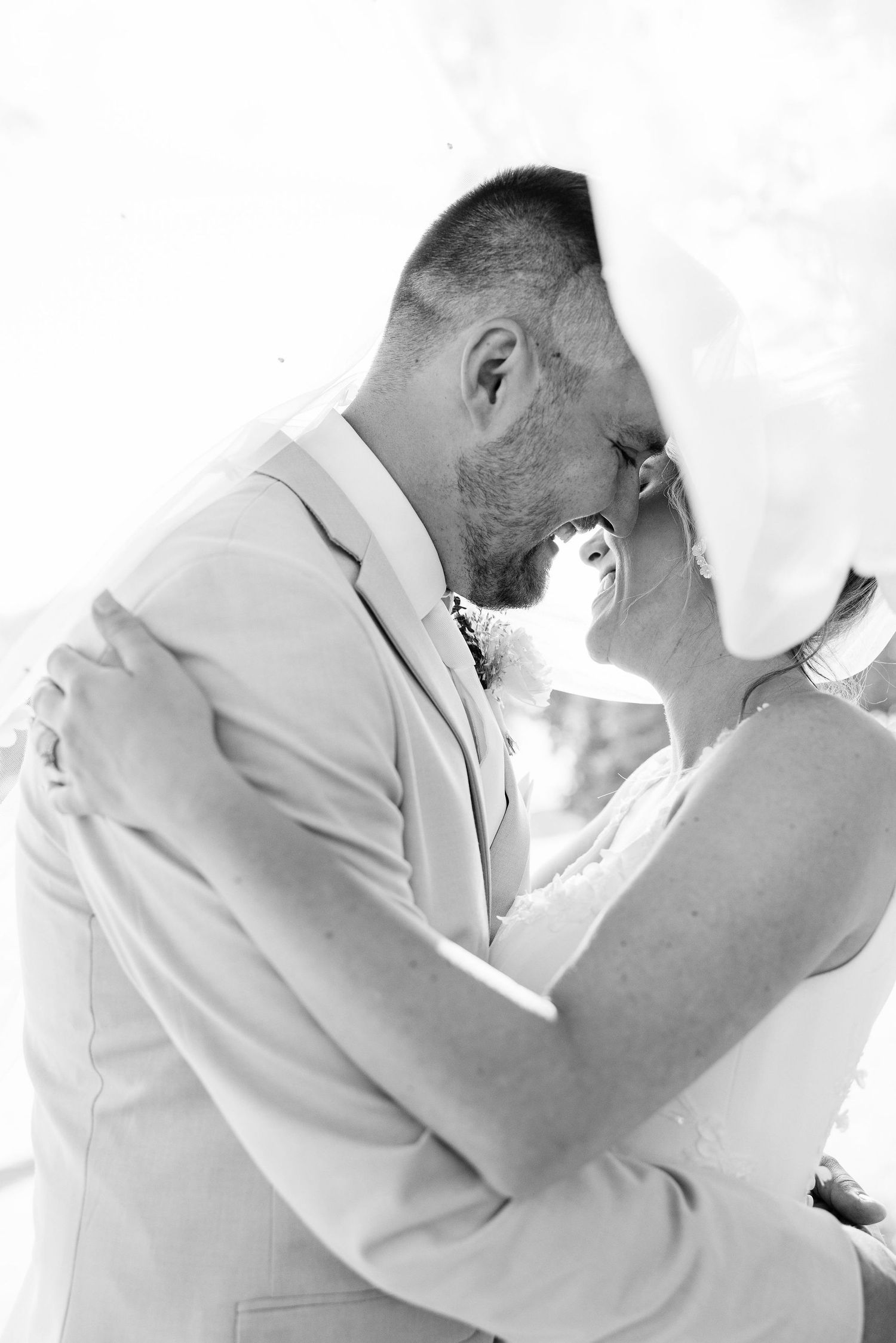 Married couple kissing under veil at Lapeer Country Club wedding in Michigan
