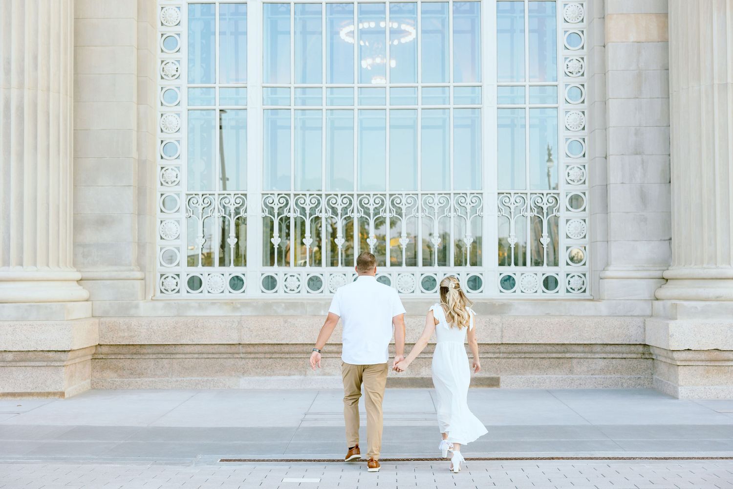 Engaged couple walking and holding hands at Michigan Central Station summer engagement session in Detroit, MI