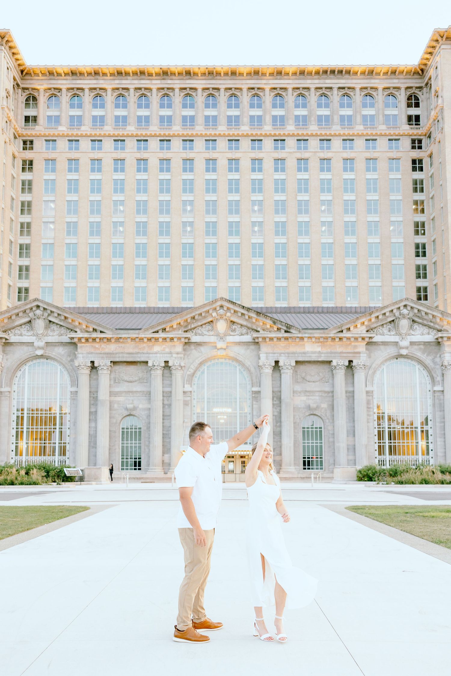 Engaged couple twirling at Michigan Central Station summer engagement session in Detroit, MI