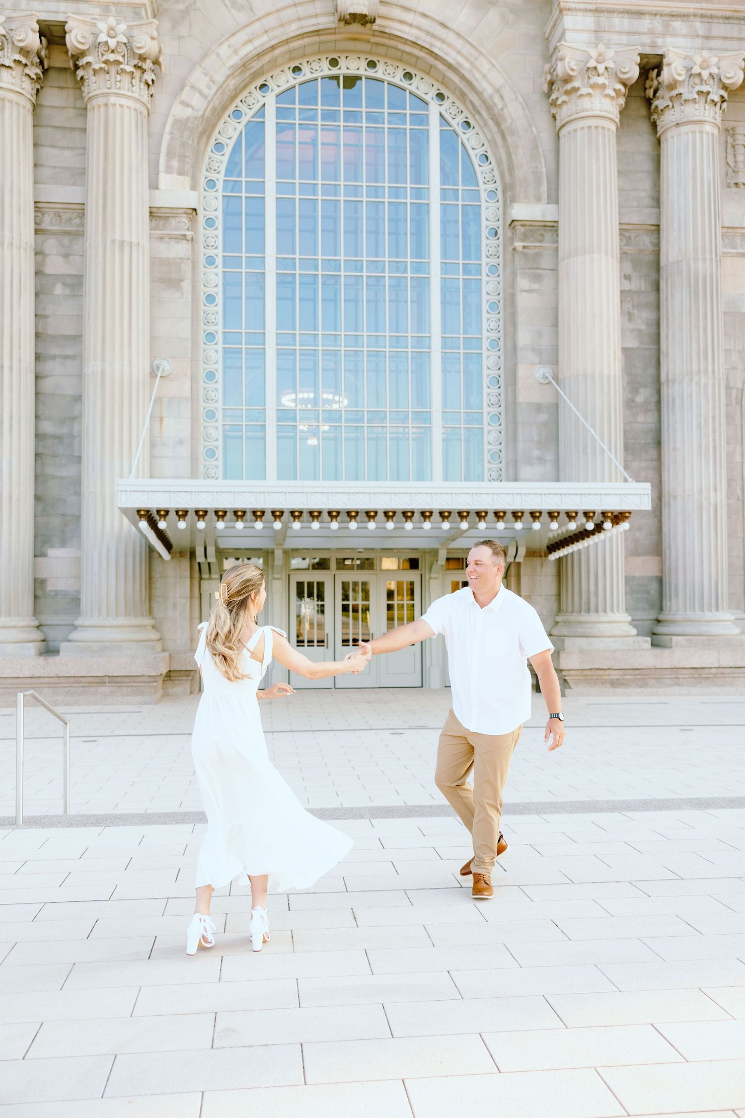Engaged couple twirling at Michigan Central Station summer engagement session in Detroit, MI