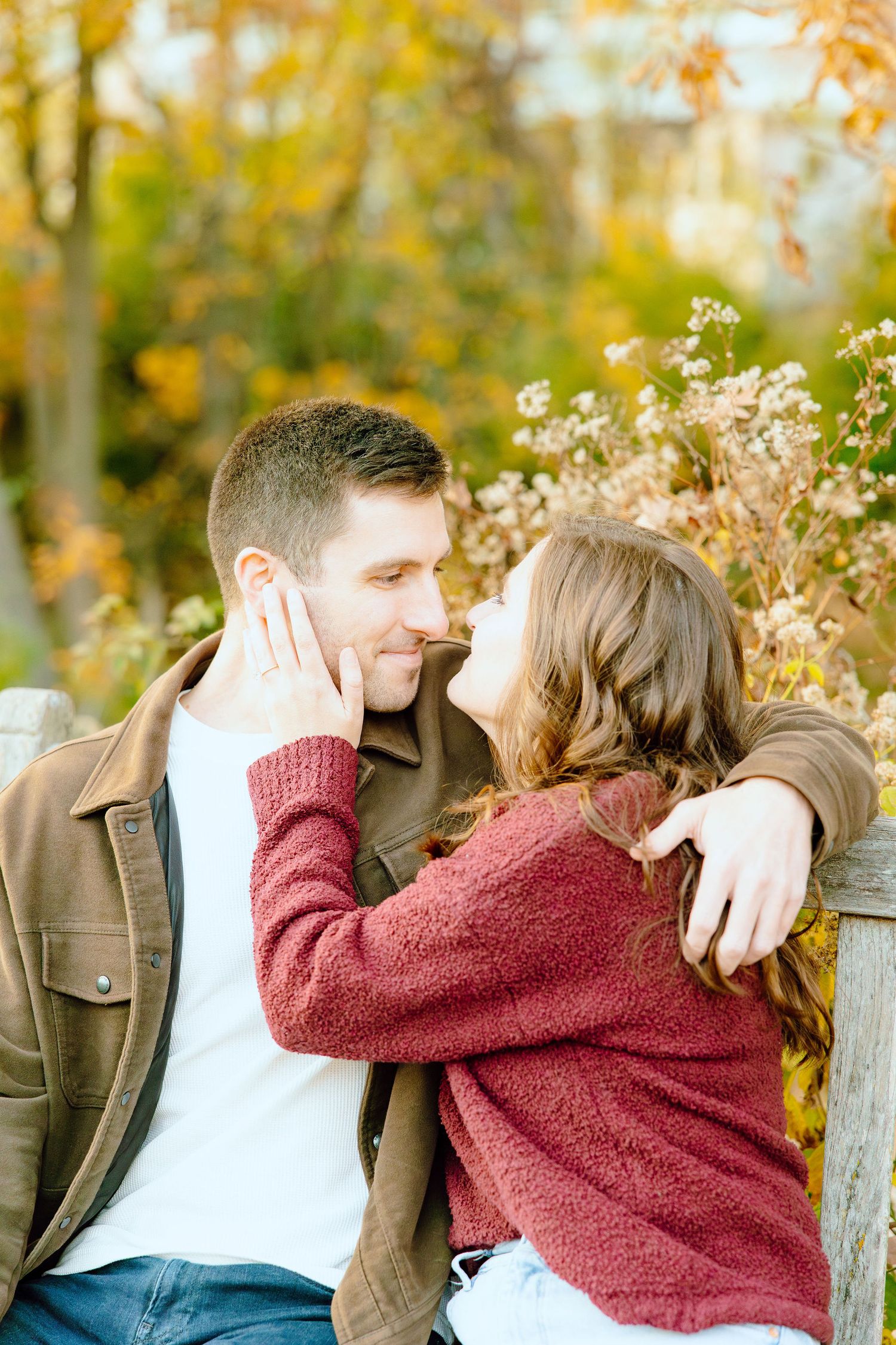 Engaged couple embracing on bench at Nichols Arboretum in Ann Arbor, MI