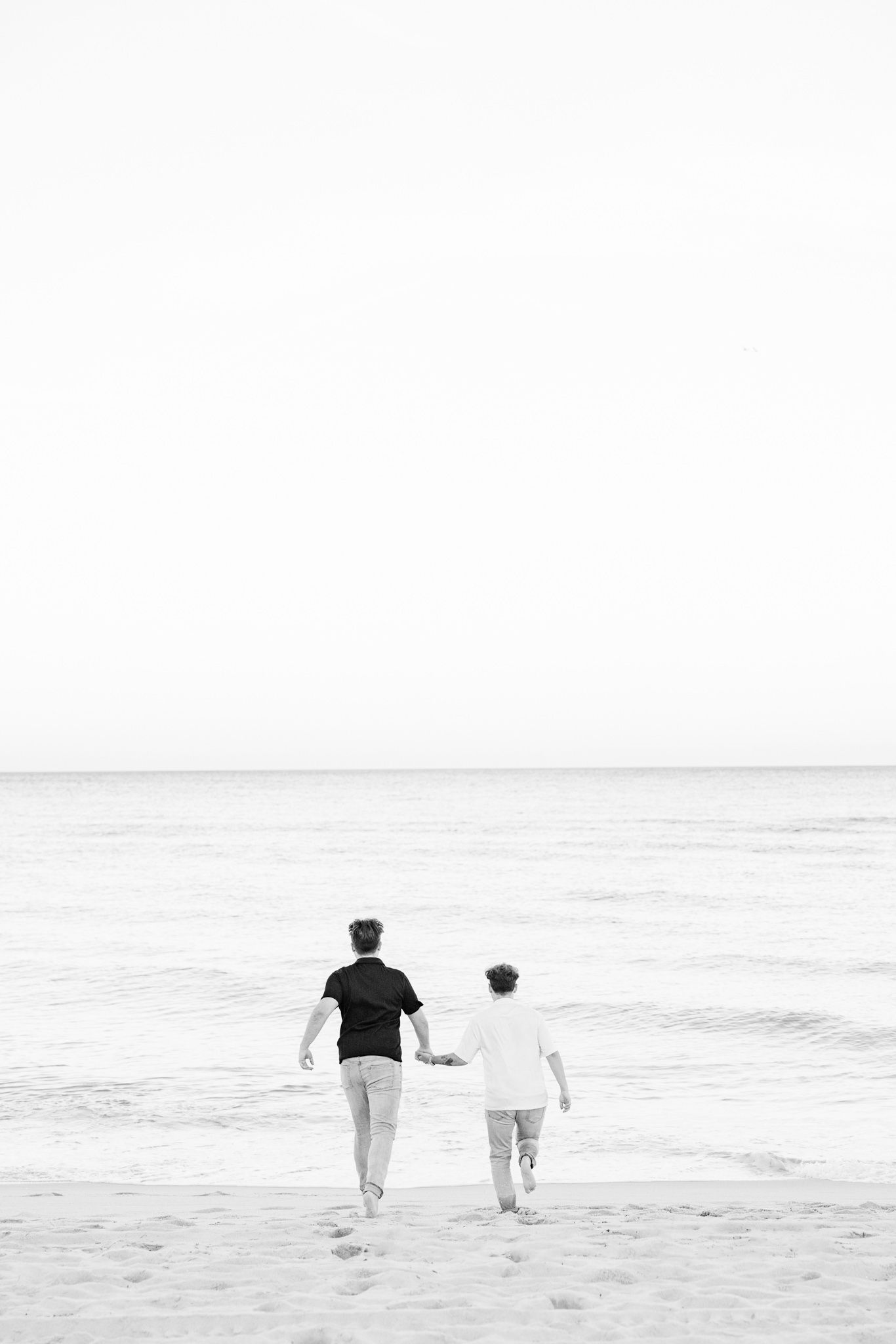 LGBTQ+ couple running and holding hands on North Miami Beach in Florida