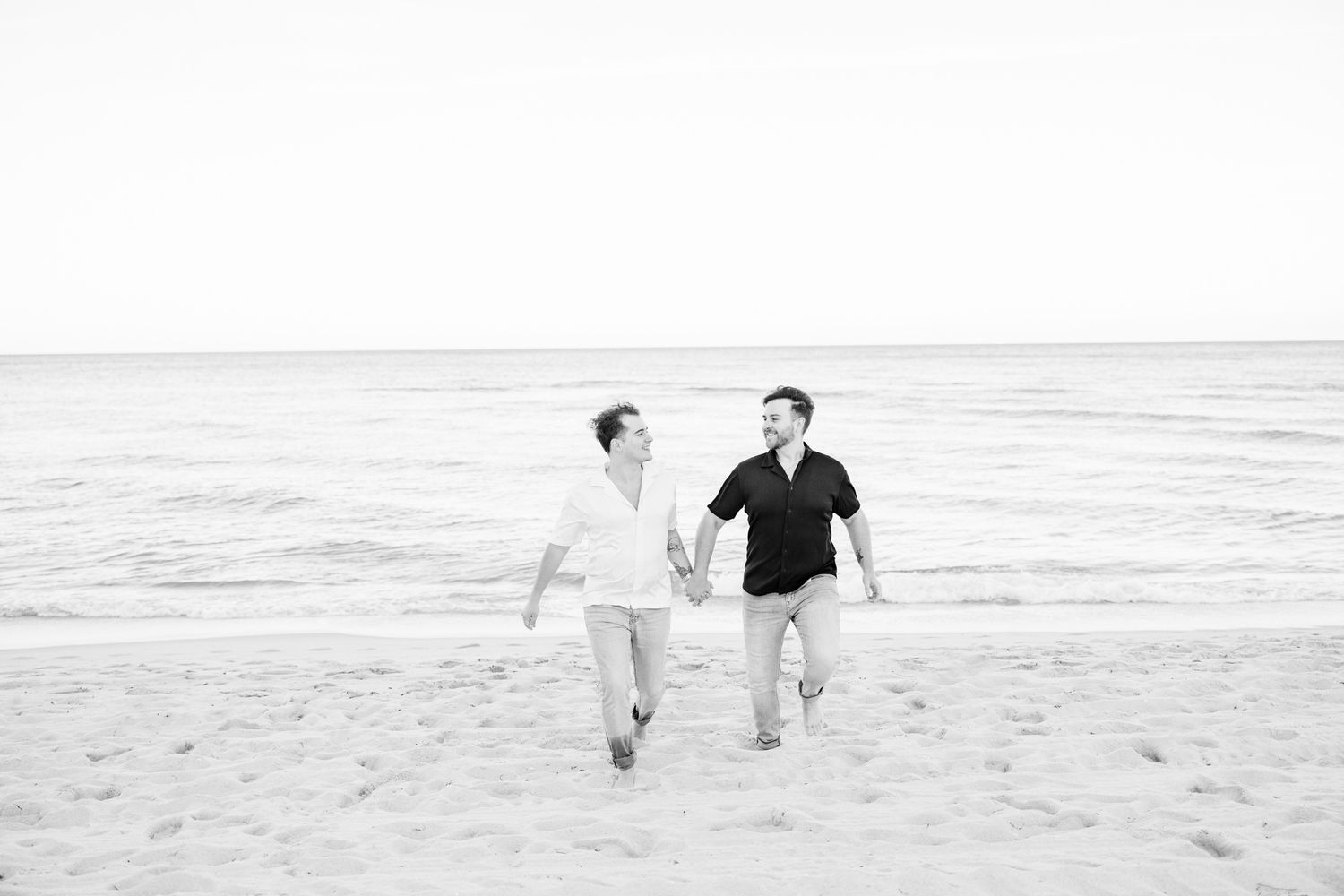 LGBTQ+ couple running and holding hands on North Miami Beach in Florida