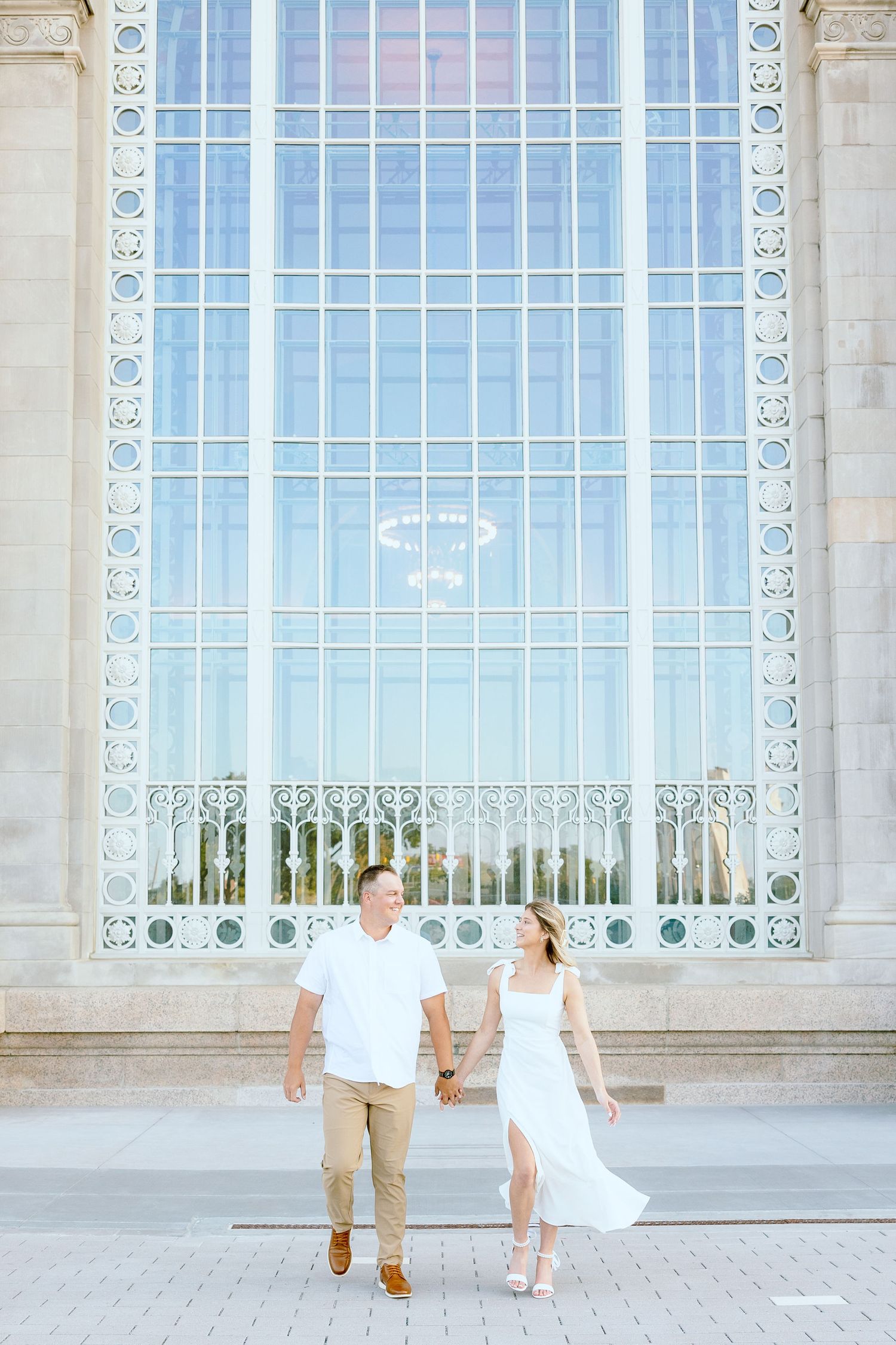 Engaged couple walking and holding hands at Michigan Central Station summer engagement session in Detroit, MI