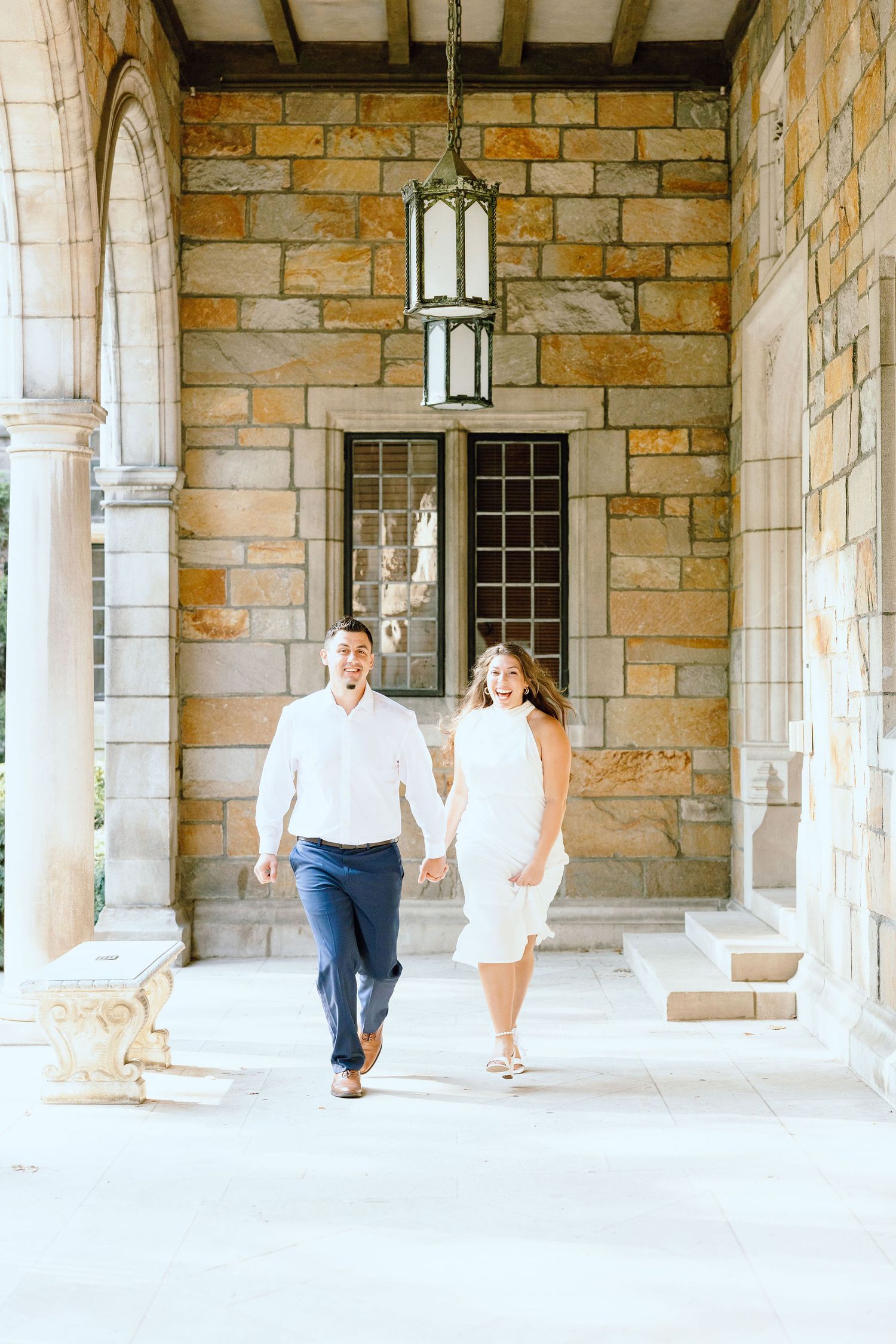 Engaged couple running and holding hands at the UofM Law Quad engagement session in Ann Arbor, MI