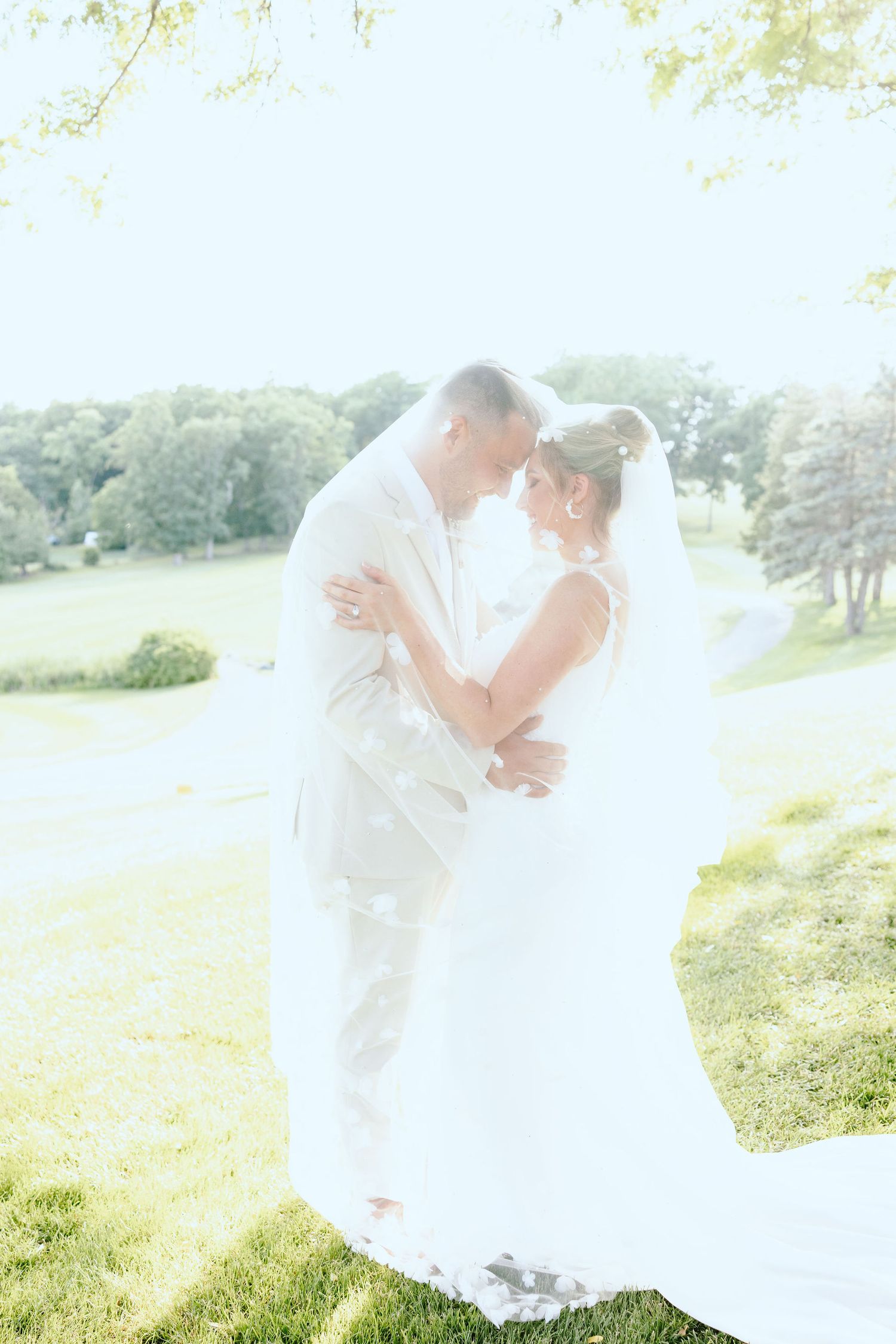 Married couple embracing under veil at Lapeer Country Club wedding in Michigan