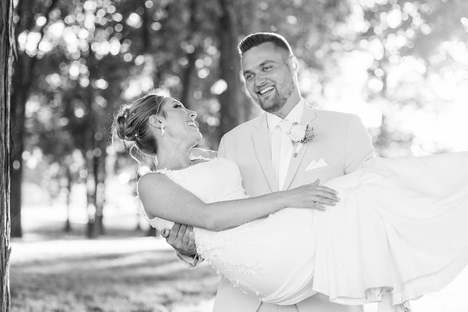 Groom carrying bride during golden hour at Lapeer Country Club forest wedding in Michigan