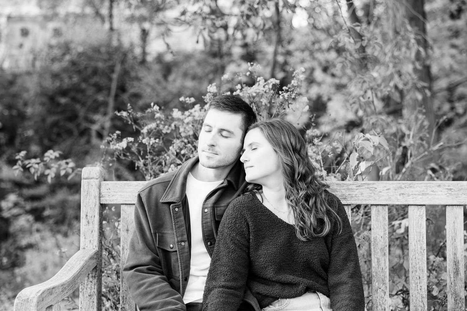 Engaged couple embracing on bench at Nichols Arboretum in Ann Arbor, MI