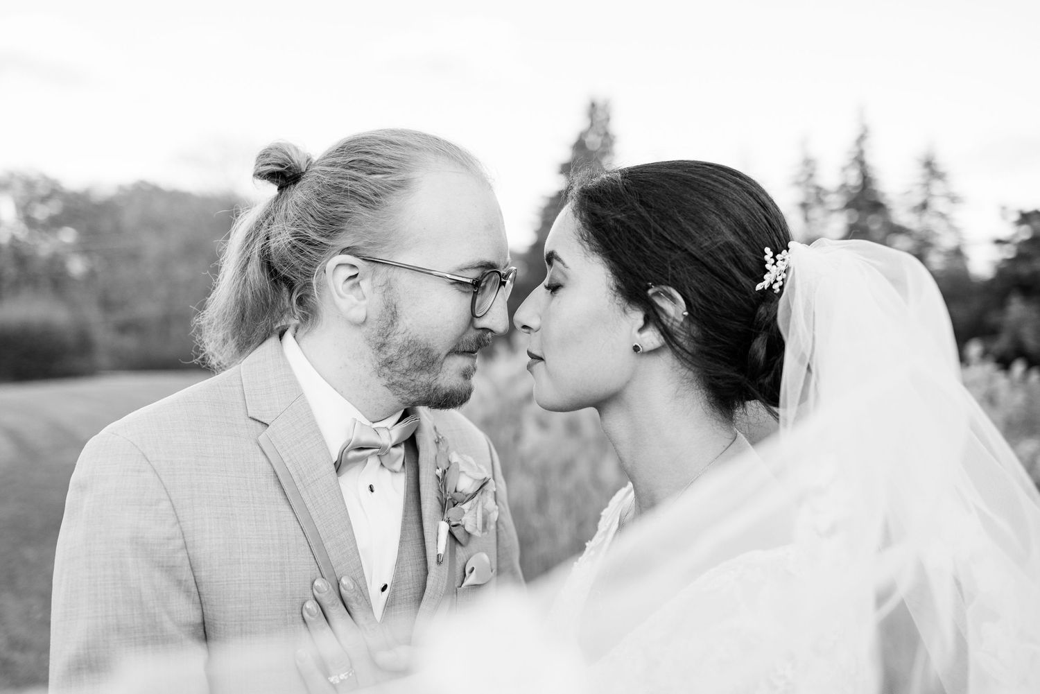 Married couple touching foreheads with veil sweeping in field of pampas grass in Novi, Michigan