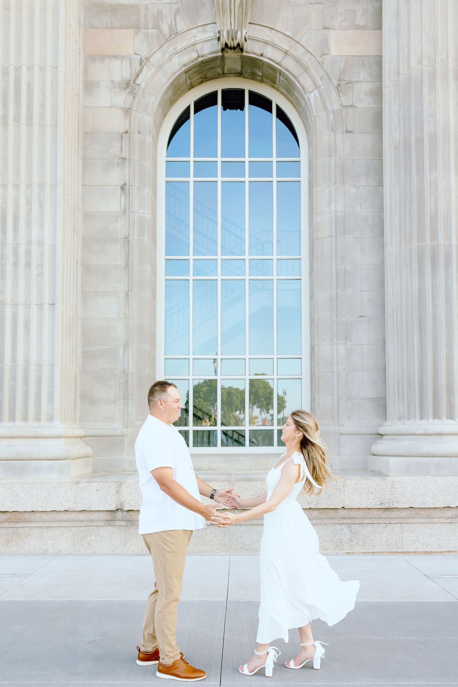 Engaged couple walking and holding hands at Michigan Central Station summer engagement session in Detroit, MI