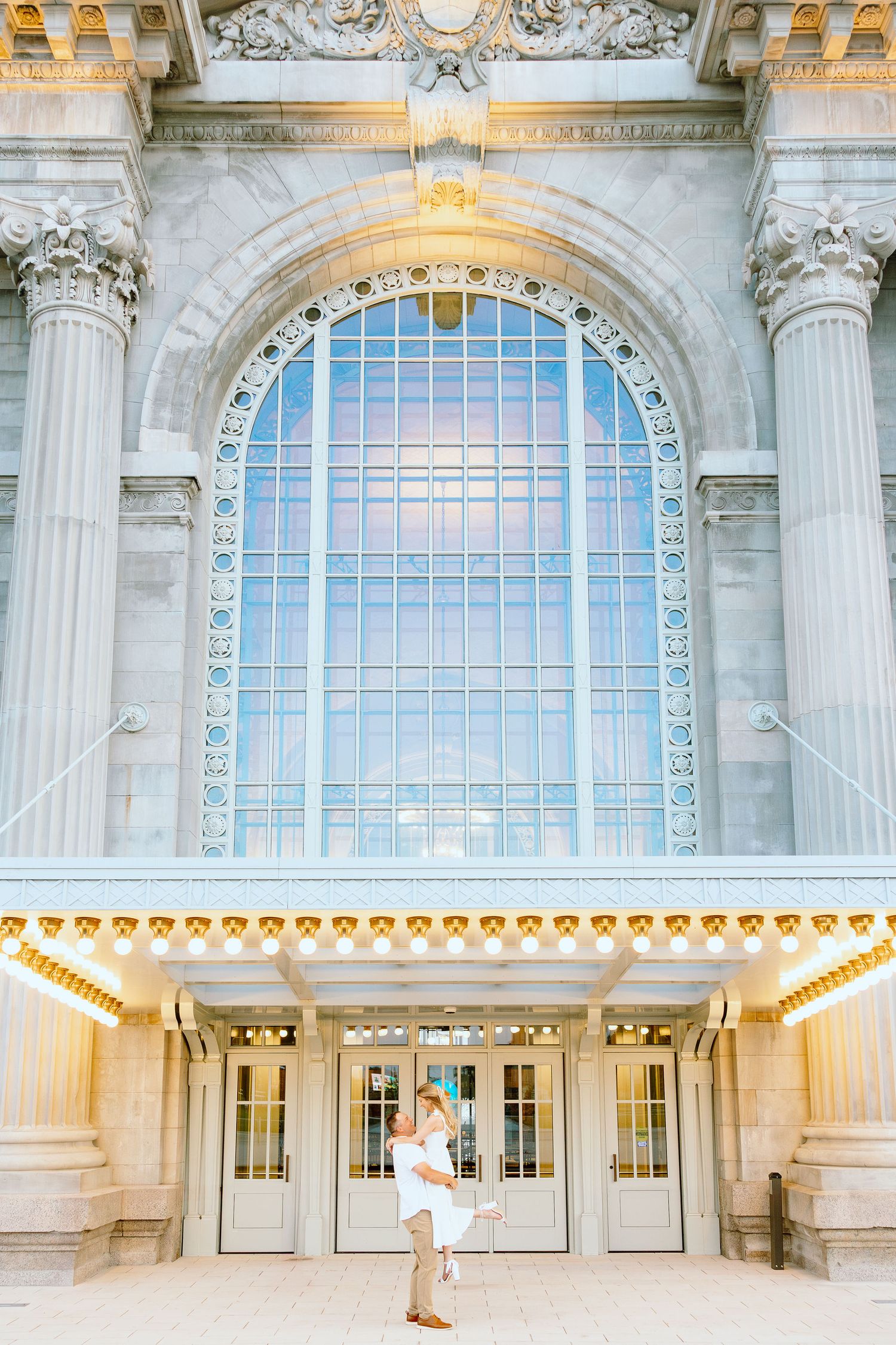 Man lifting woman at Michigan Central Station summer engagement session in Detroit, MI