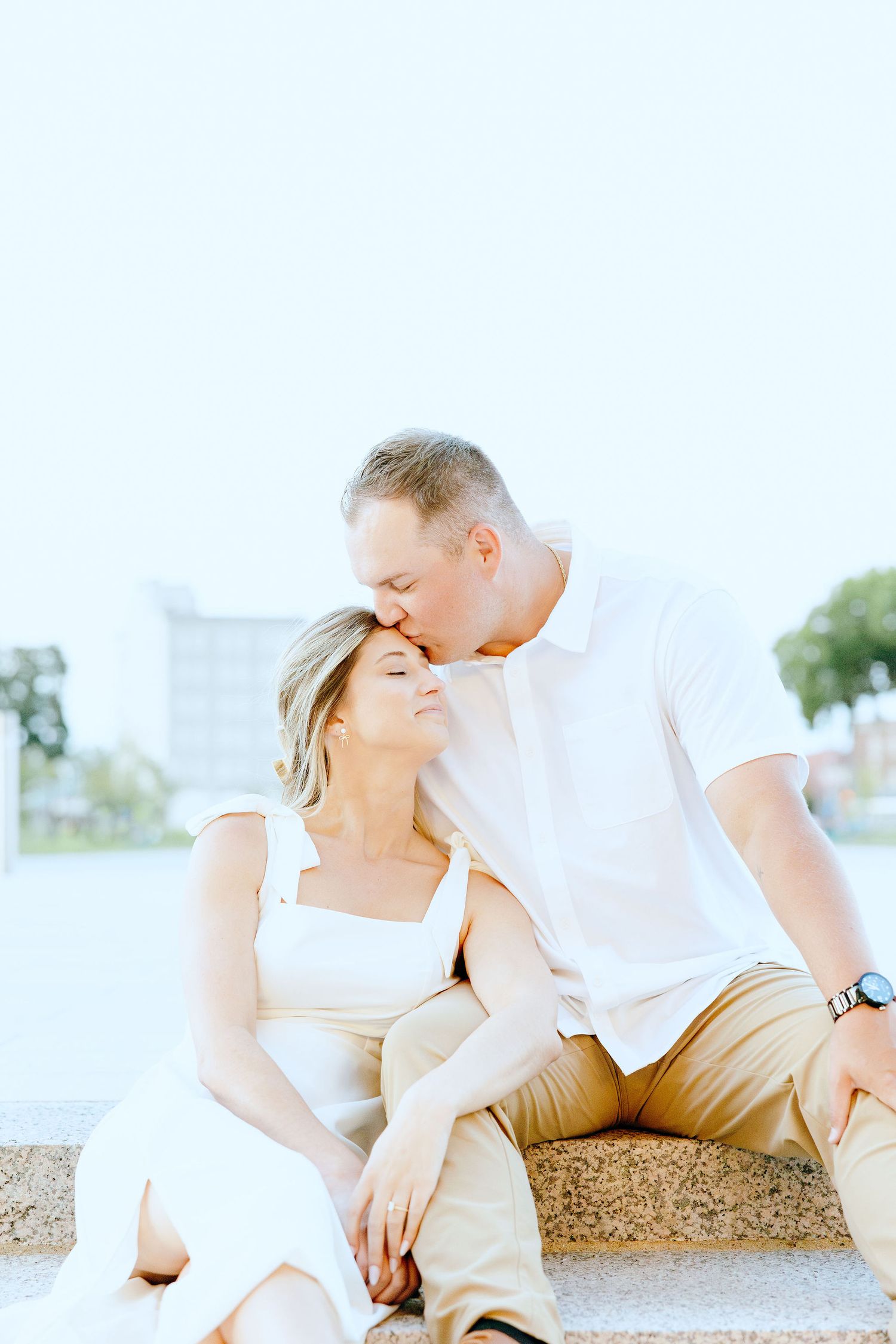 Engaged couple embracing on bench at Michigan Central Station in Detroit, MI