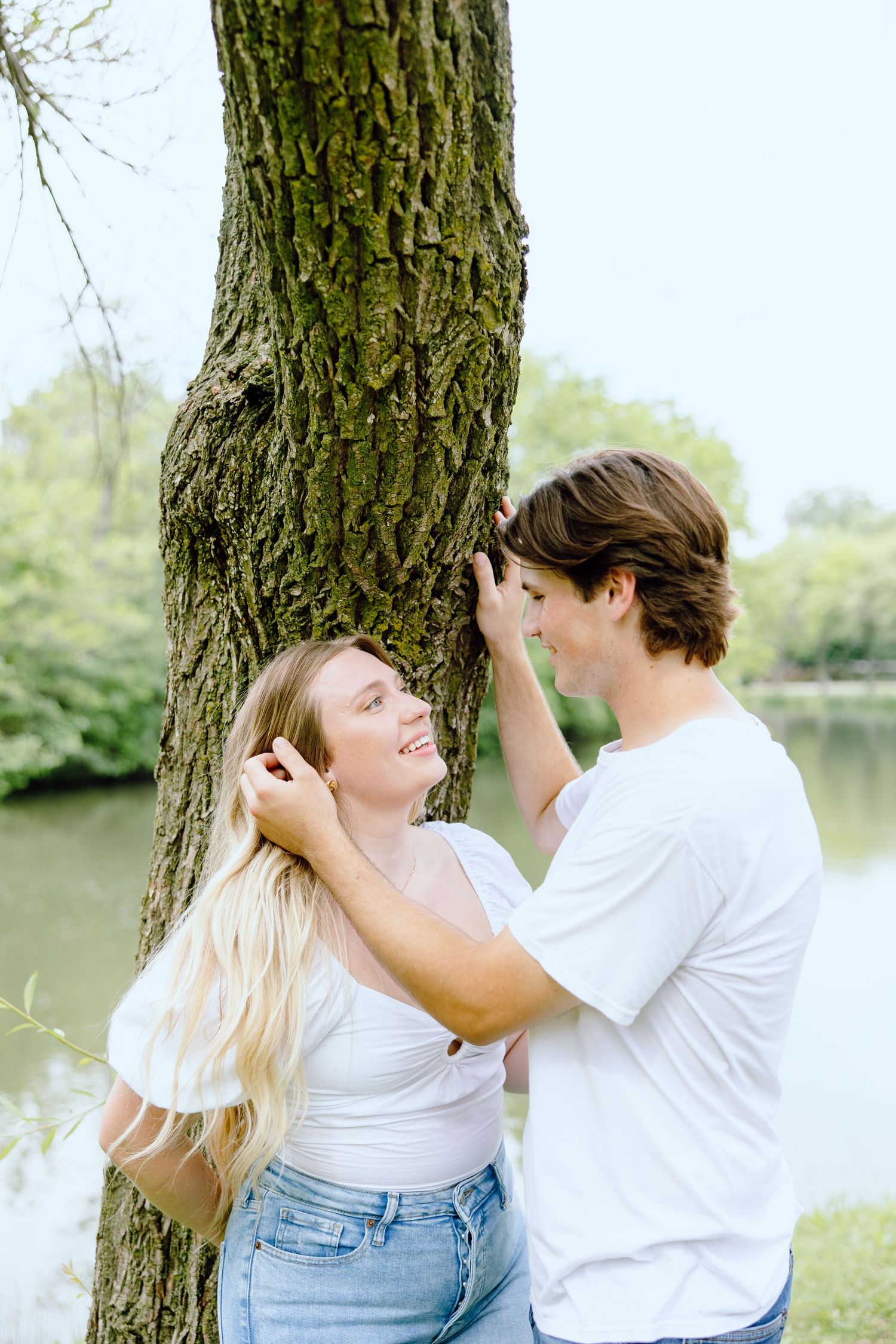 Engaged couple leaning against tree at Greenfield Village