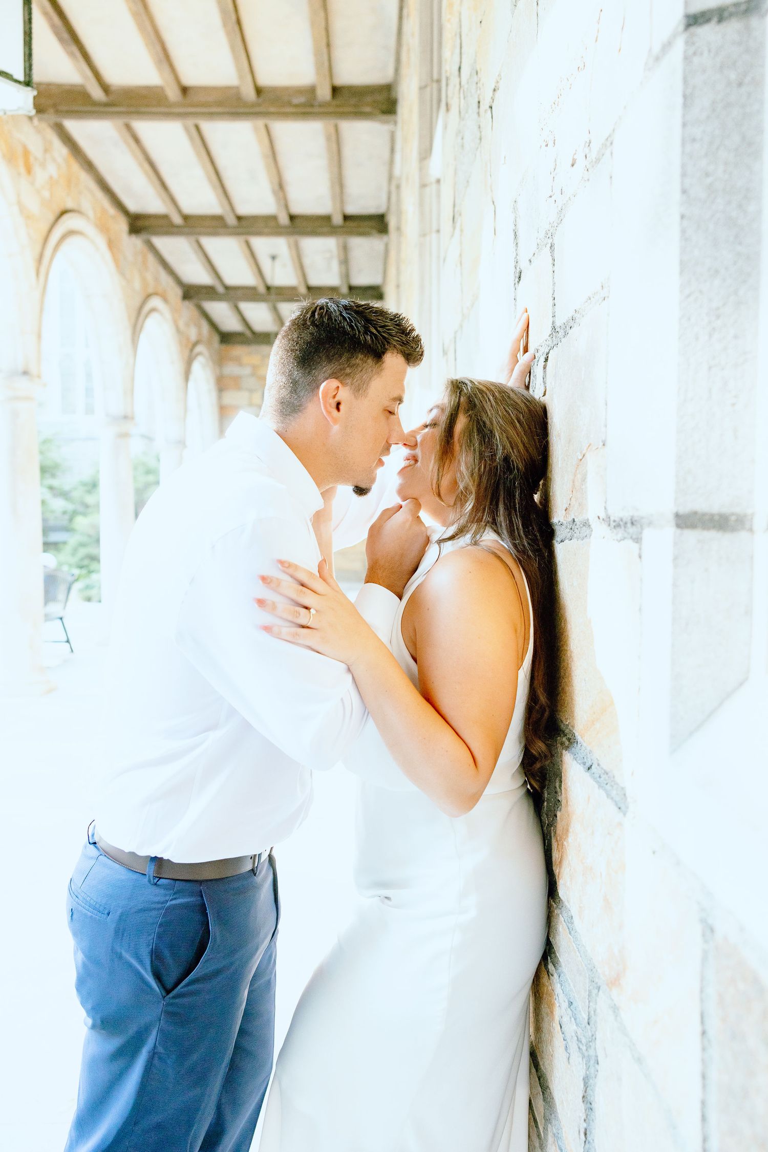 Engaged couple kissing against wall at the University of Michigan Law Quad engagement session in Ann Arbor, MI