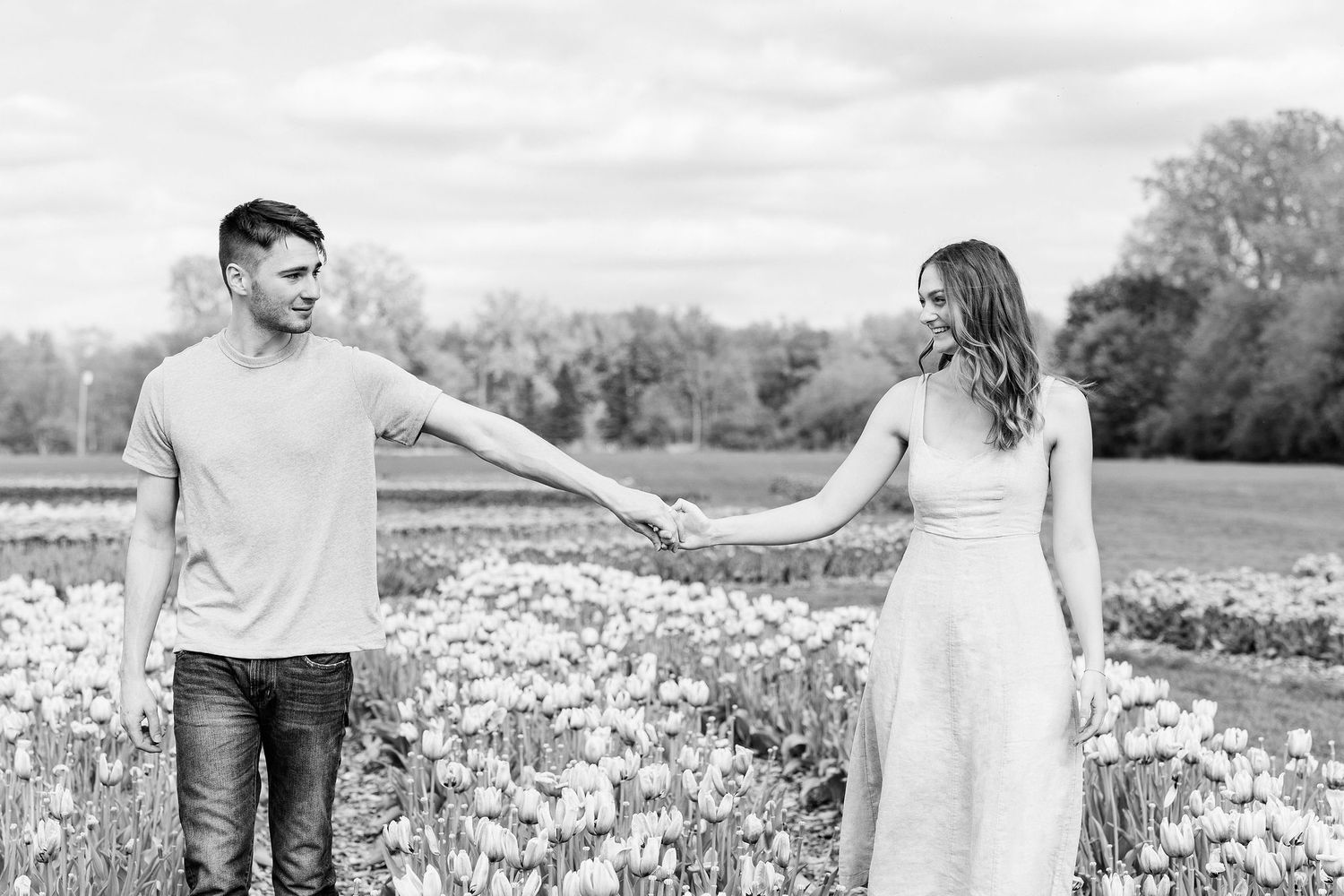 Engaged couple walking and holding hands at DeBuck's tulip field spring engagement session in Belleville, MI