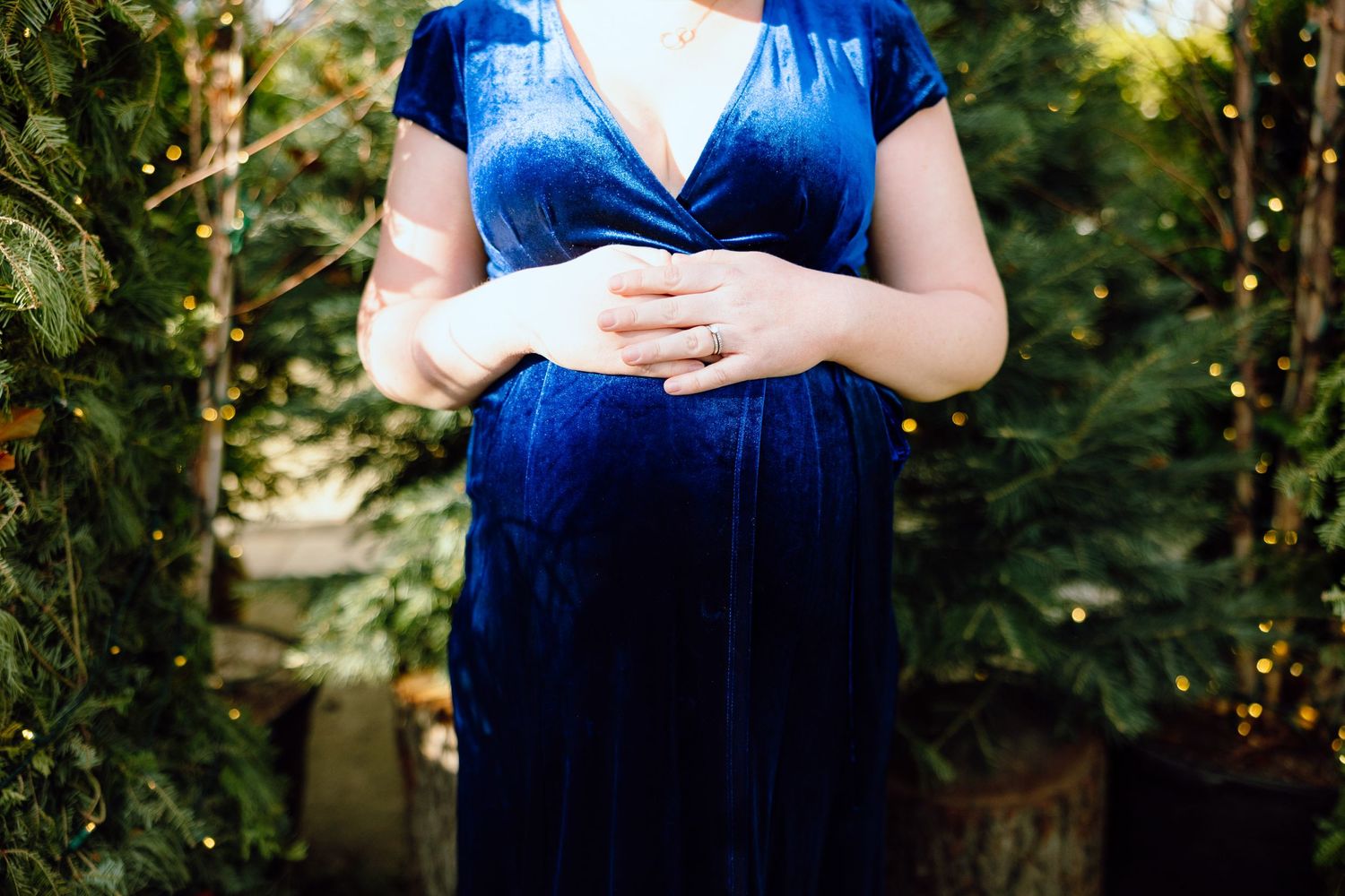 Expecting mom holding stomach in front of Christmas greenery in downtown Detroit, MI