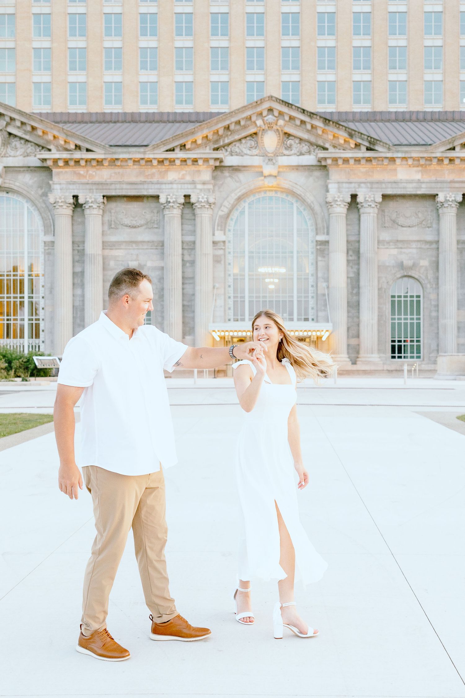 Engaged couple twirling at Michigan Central Station summer engagement session in Detroit, MI