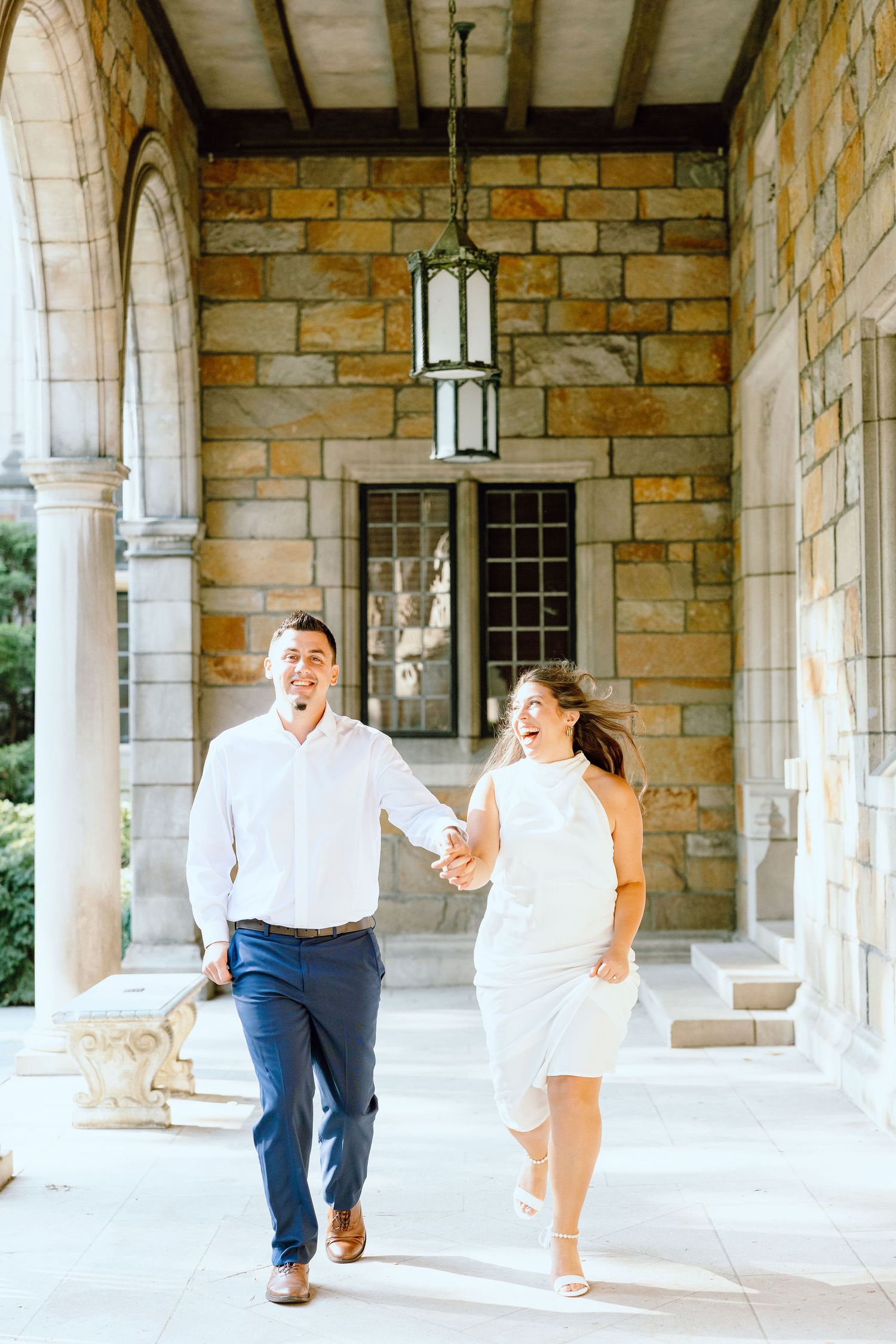 Engaged couple running and holding hands at the UofM Law Quad engagement session in Ann Arbor, MI