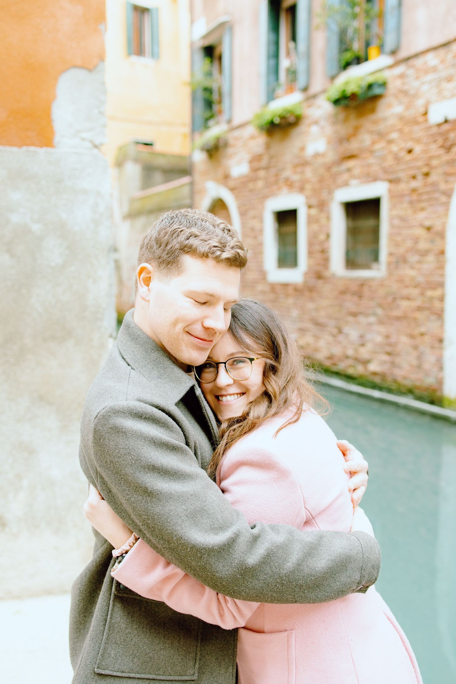 Engaged couple hugs and laughs in front of Venice Canal in Italy