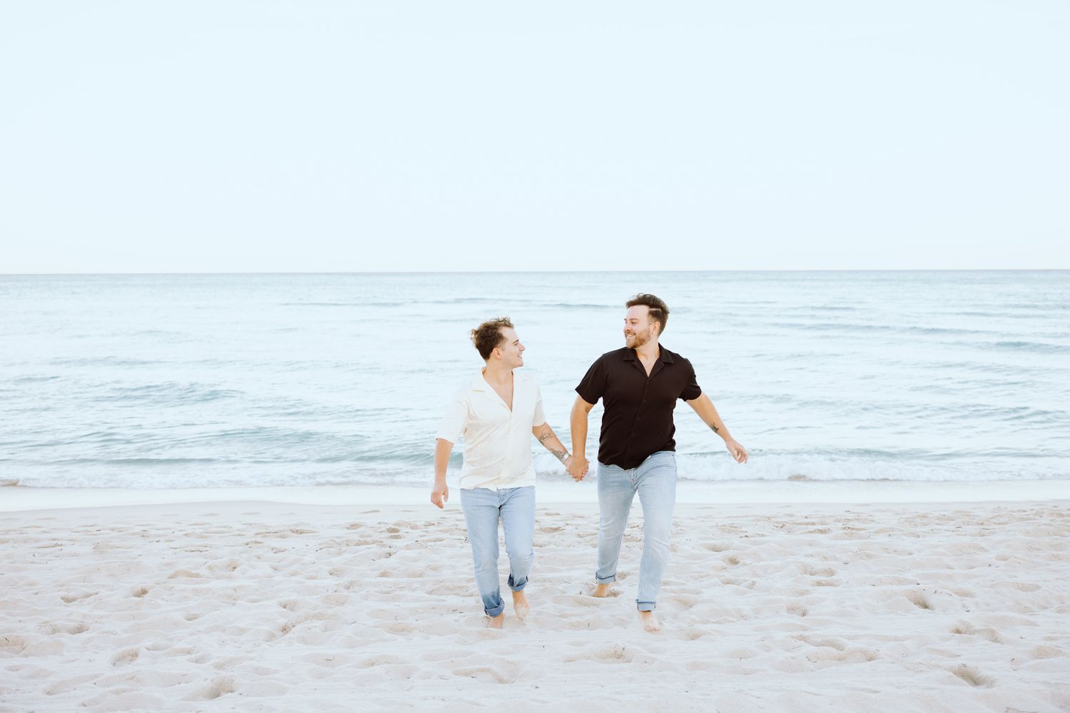 LGBTQ+ couple running and holding hands on North Miami Beach in Florida