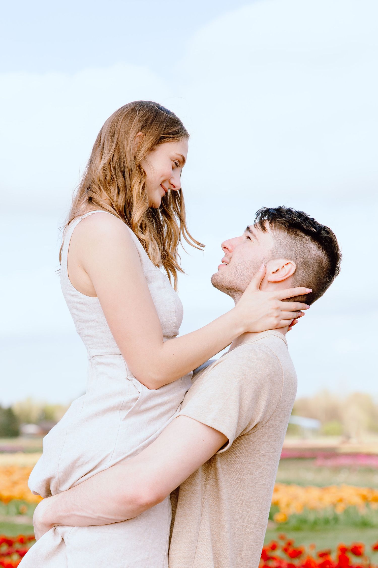 Man lifting woman at DeBuck's tulip field spring engagement session in Belleville, MI
Engaged couple sitting on cabin at DeBuck's tulip fiel
