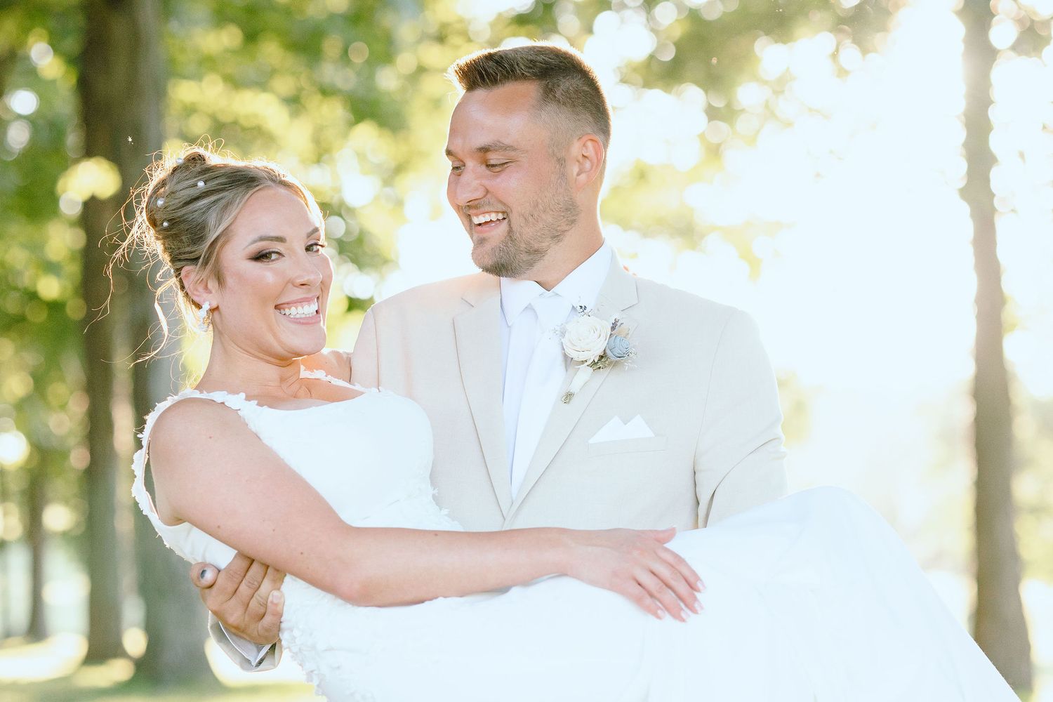 Groom carrying bride during golden hour at Lapeer Country Club forest wedding in Michigan