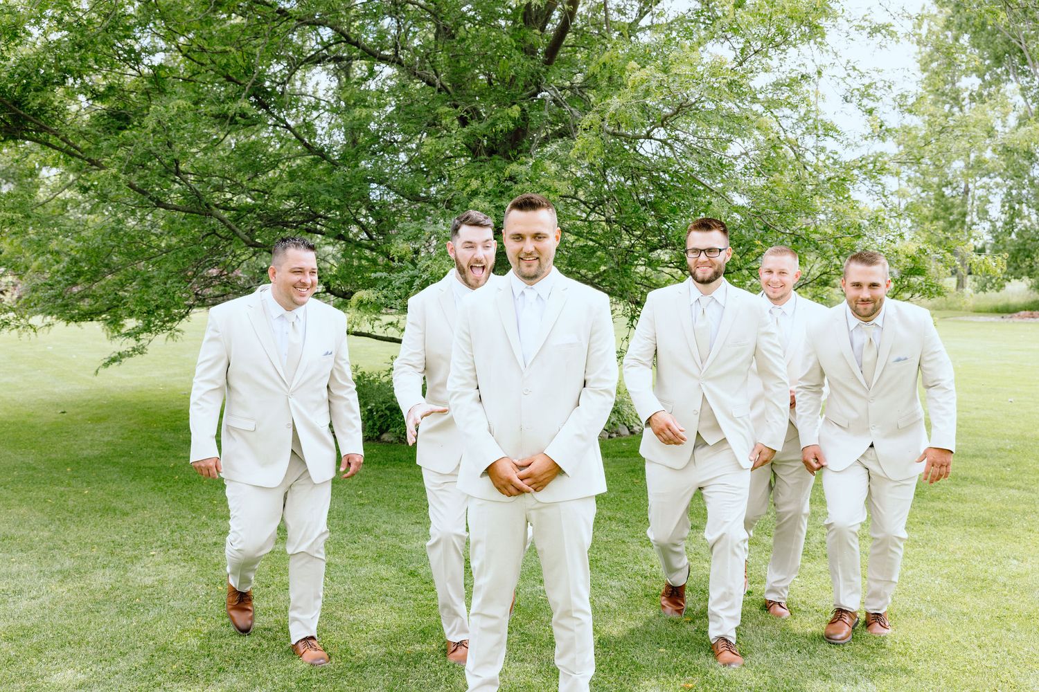 Groomsmen running towards groom at Lapeer Country Club wedding in Michigan
