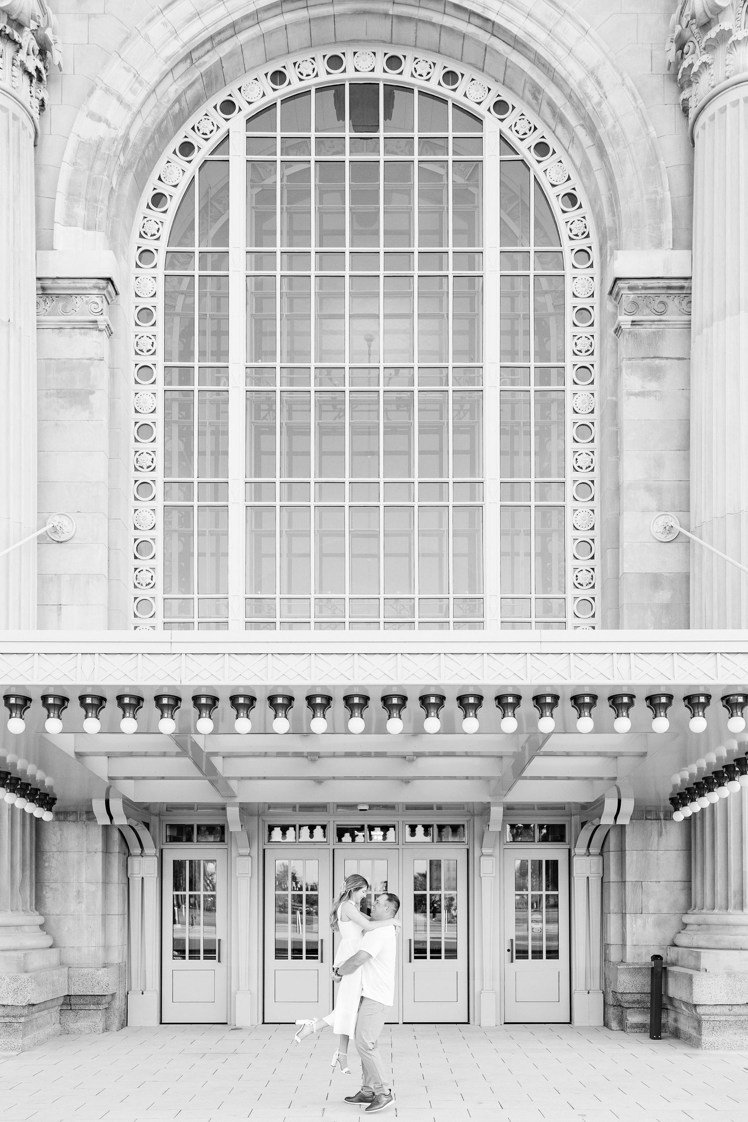 Man lifting woman at Michigan Central Station summer engagement session in Detroit, MI
