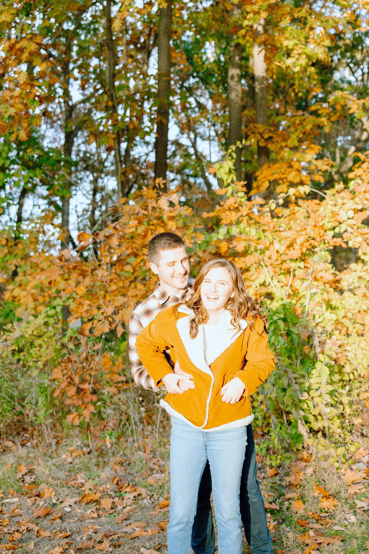 Engaged couple embracing in forest at Nichols Arboretum fall engagement session in Ann Arbor, MI